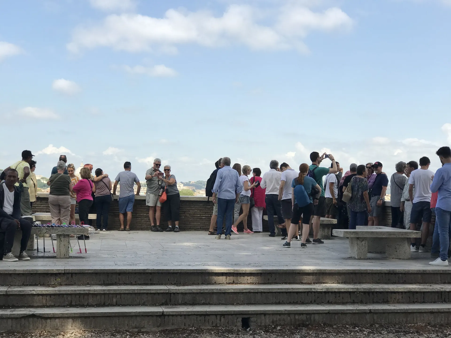 Visitors crowding the Aventine belvedere terrace railing at midday.