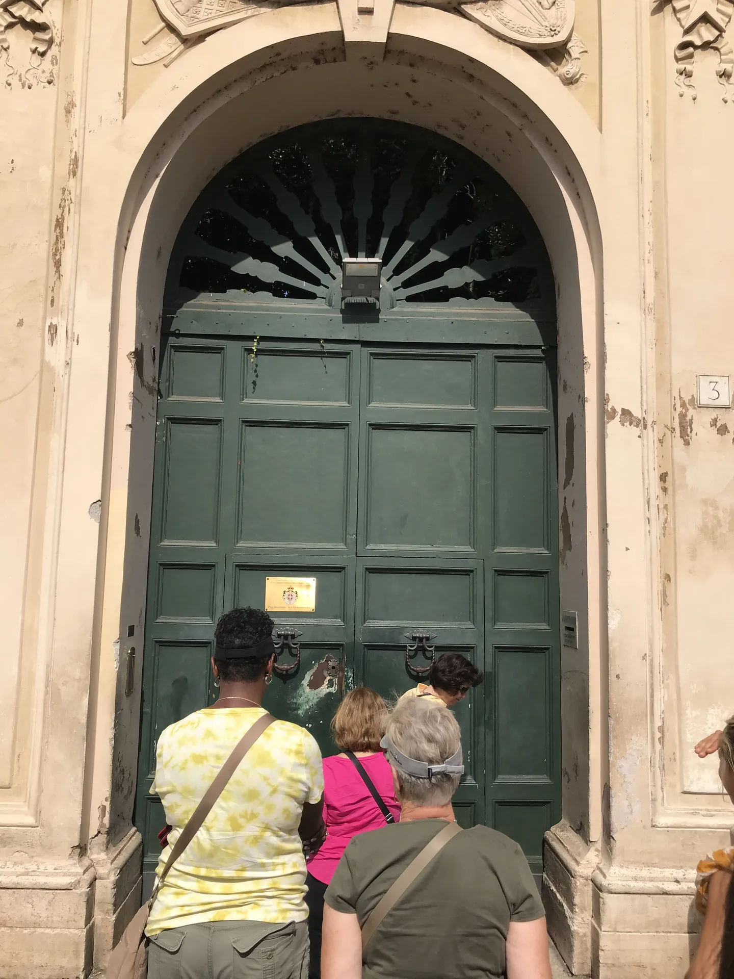 Visitors peering through the keyhole in the green Priory of Malta door on the Aventine.