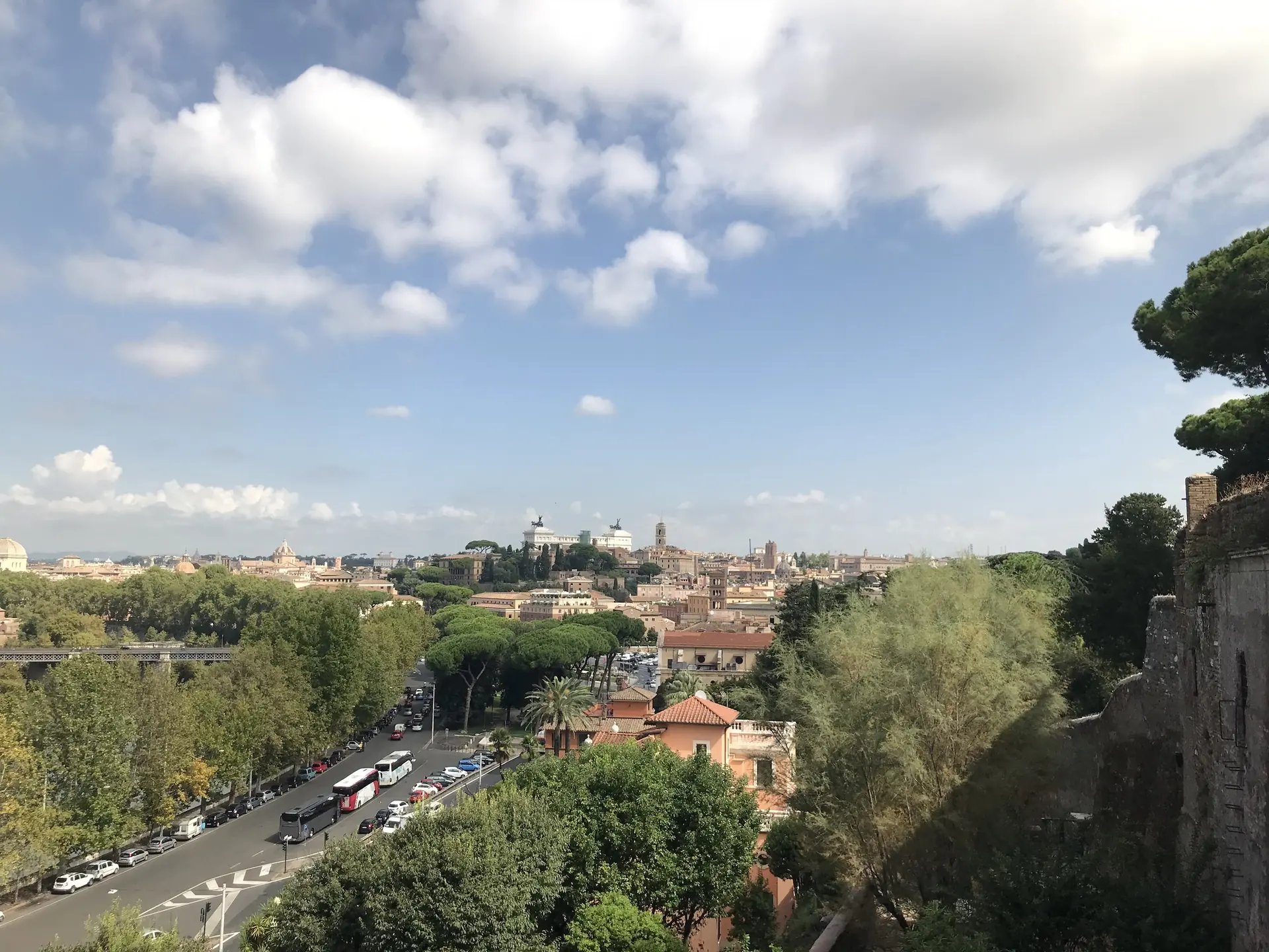 View from the Aventine over a brick wall down to the riverside road and the city.
