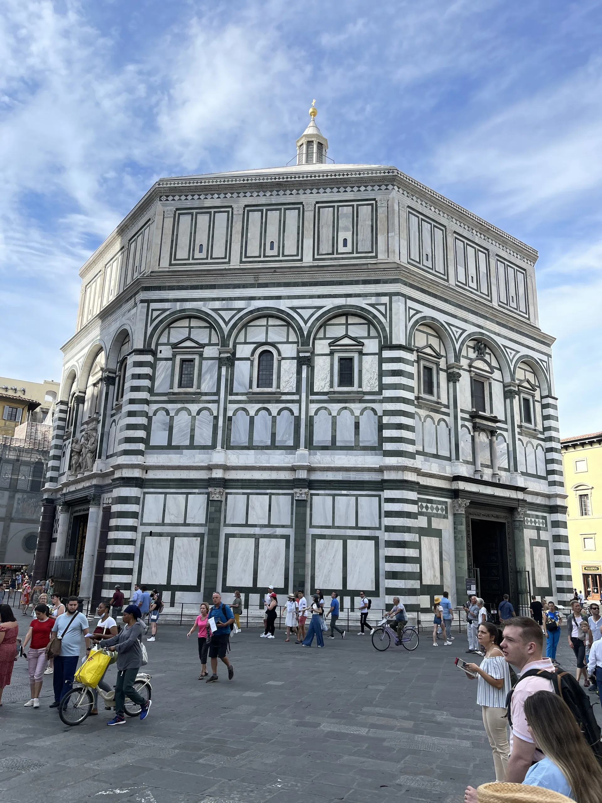 The octagonal Baptistery of San Giovanni in Florence, faced in green and white marble, under a blue sky