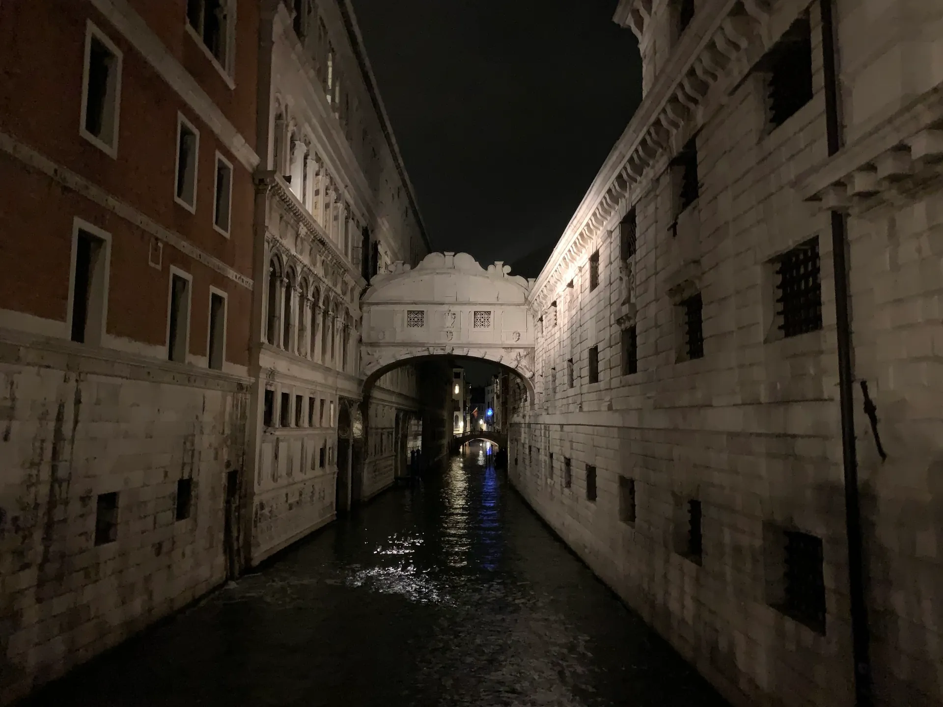 The enclosed Bridge of Sighs lit at night over the narrow Rio di Palazzo