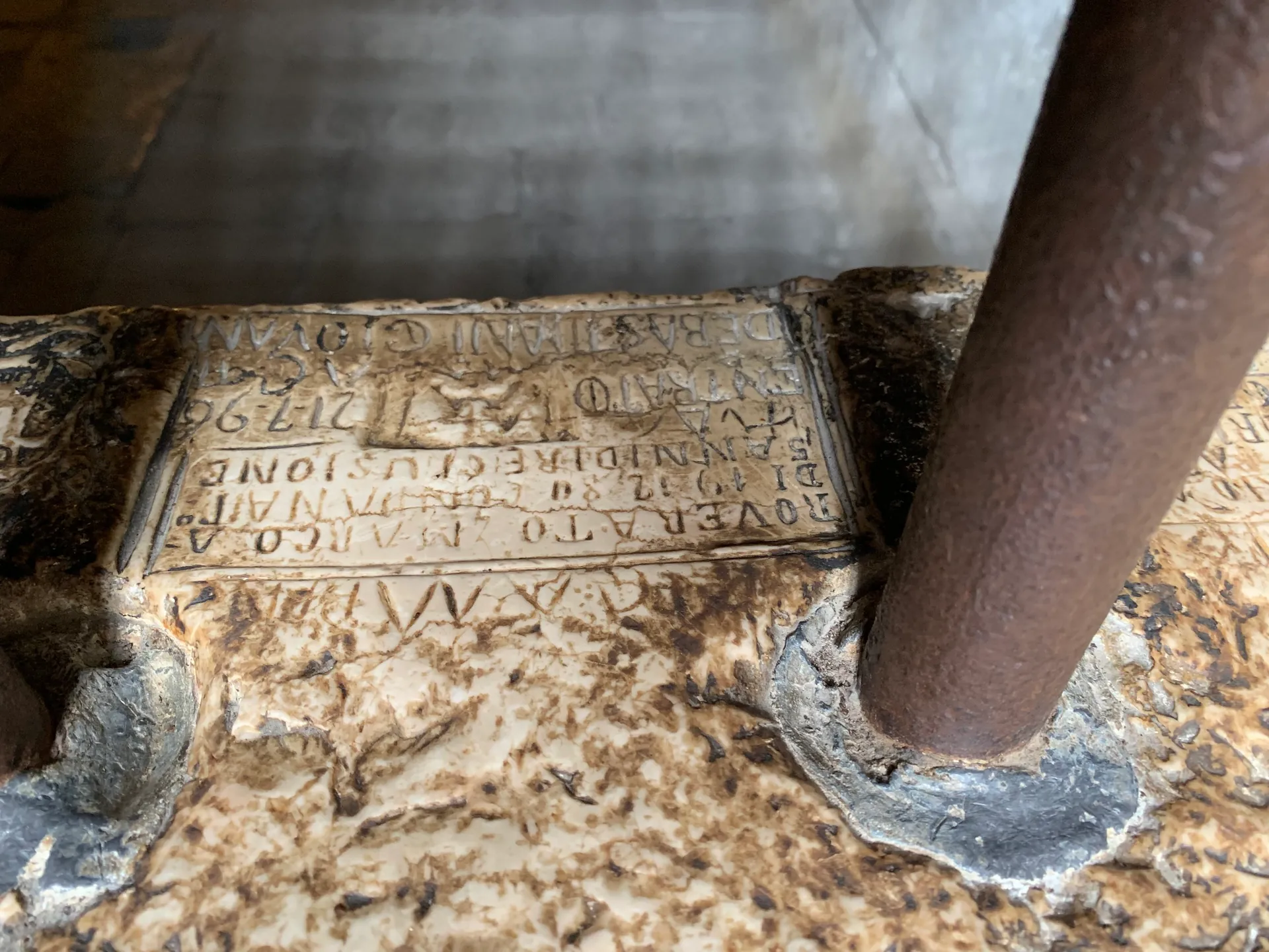 Prisoners' carved graffiti on the stone wall of a cell beside an iron column