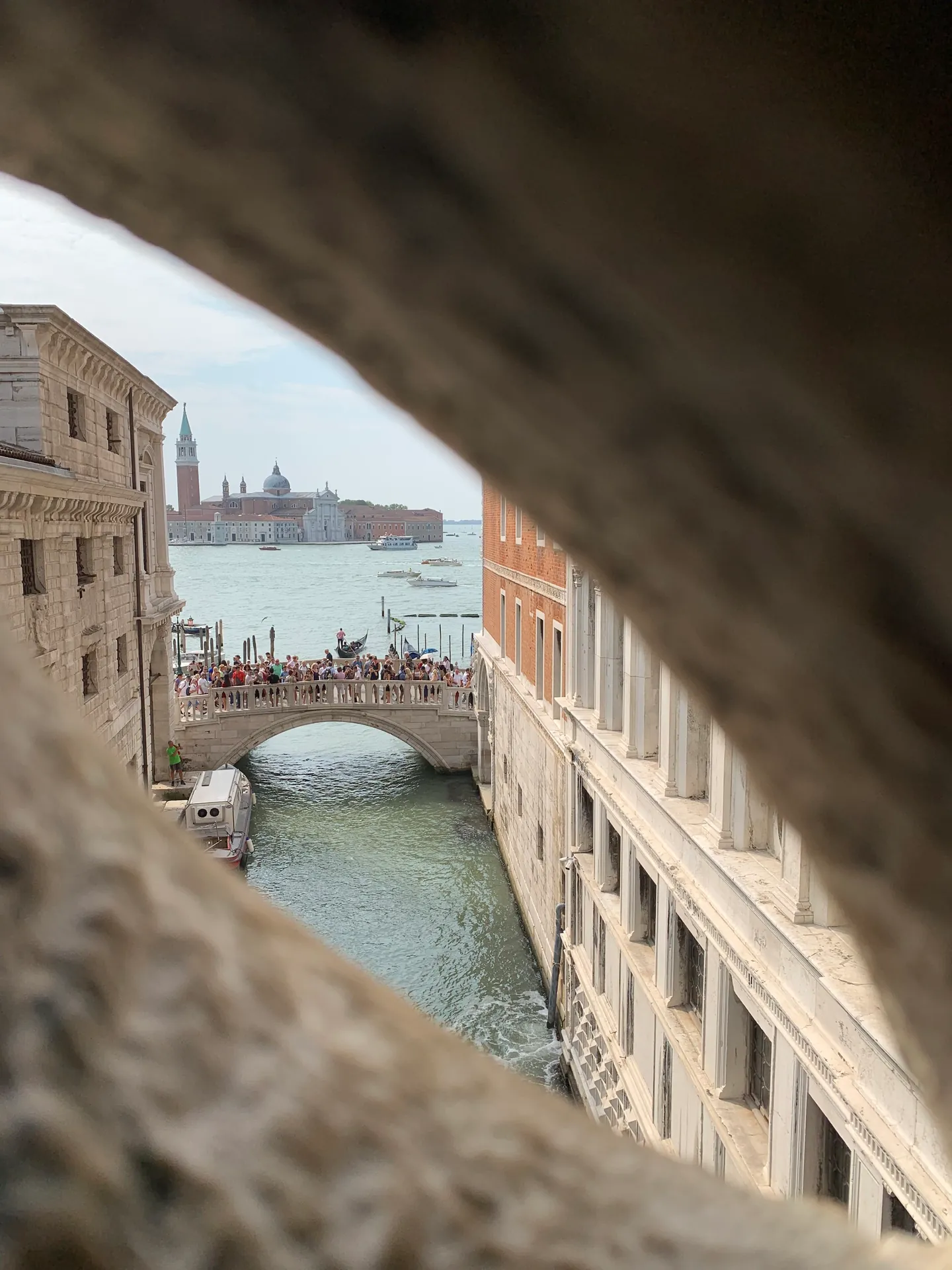 A Venetian canal and bridge seen through an opening in the Bridge of Sighs