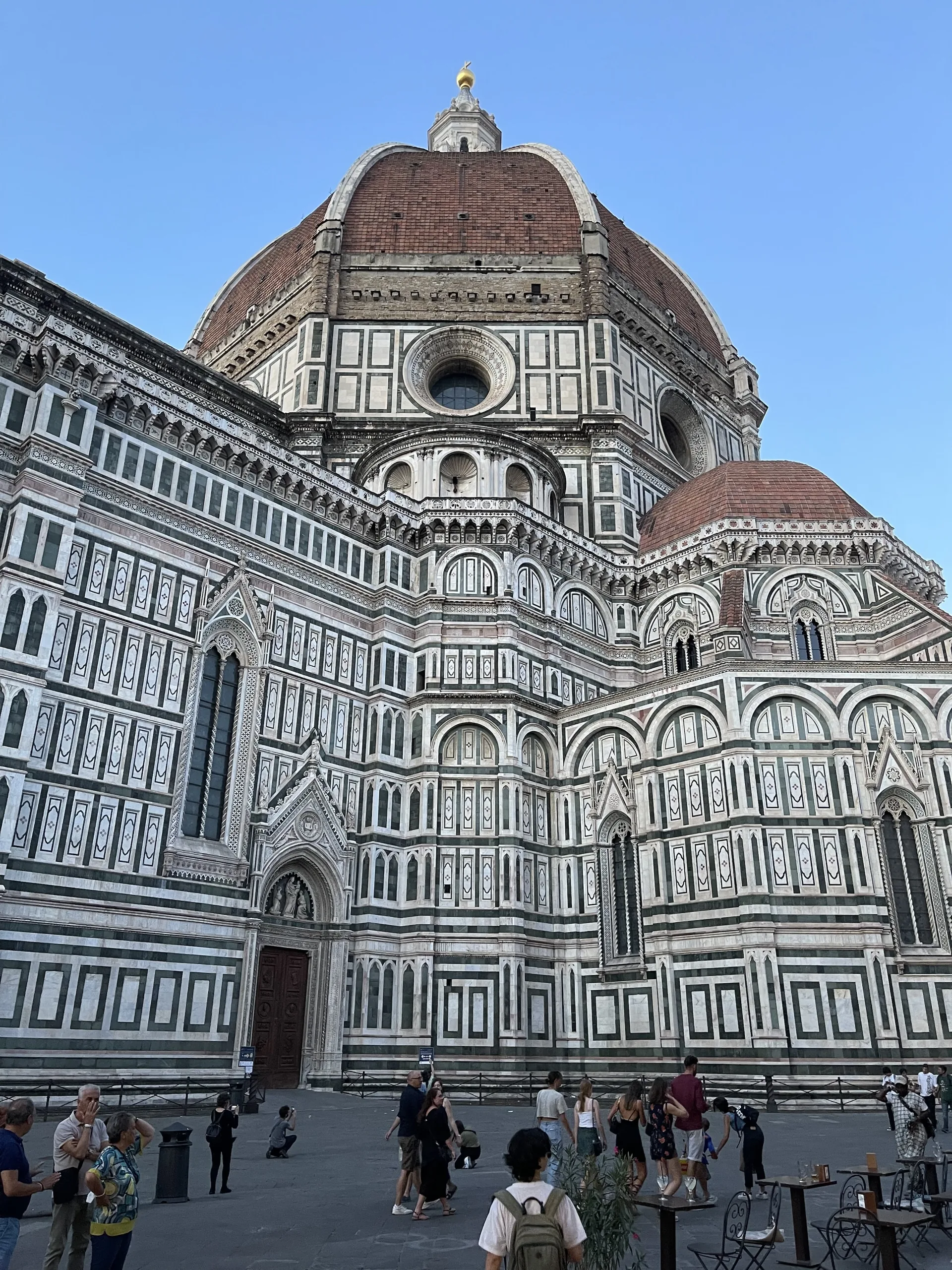 Brunelleschi's dome rising over the marble flank of Florence Cathedral against a blue sky