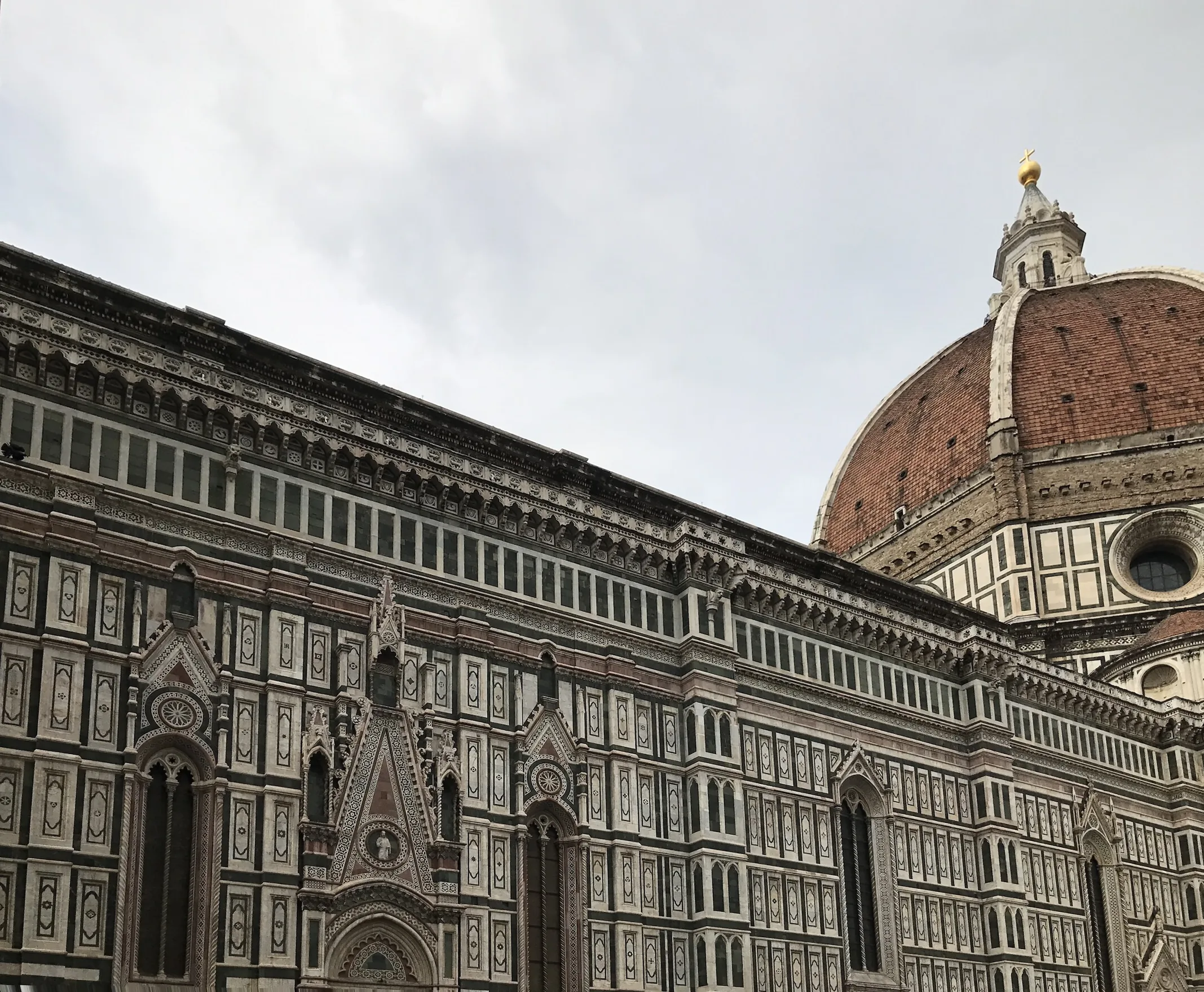 The dome rising above the green and white marble of the cathedral from the piazza
