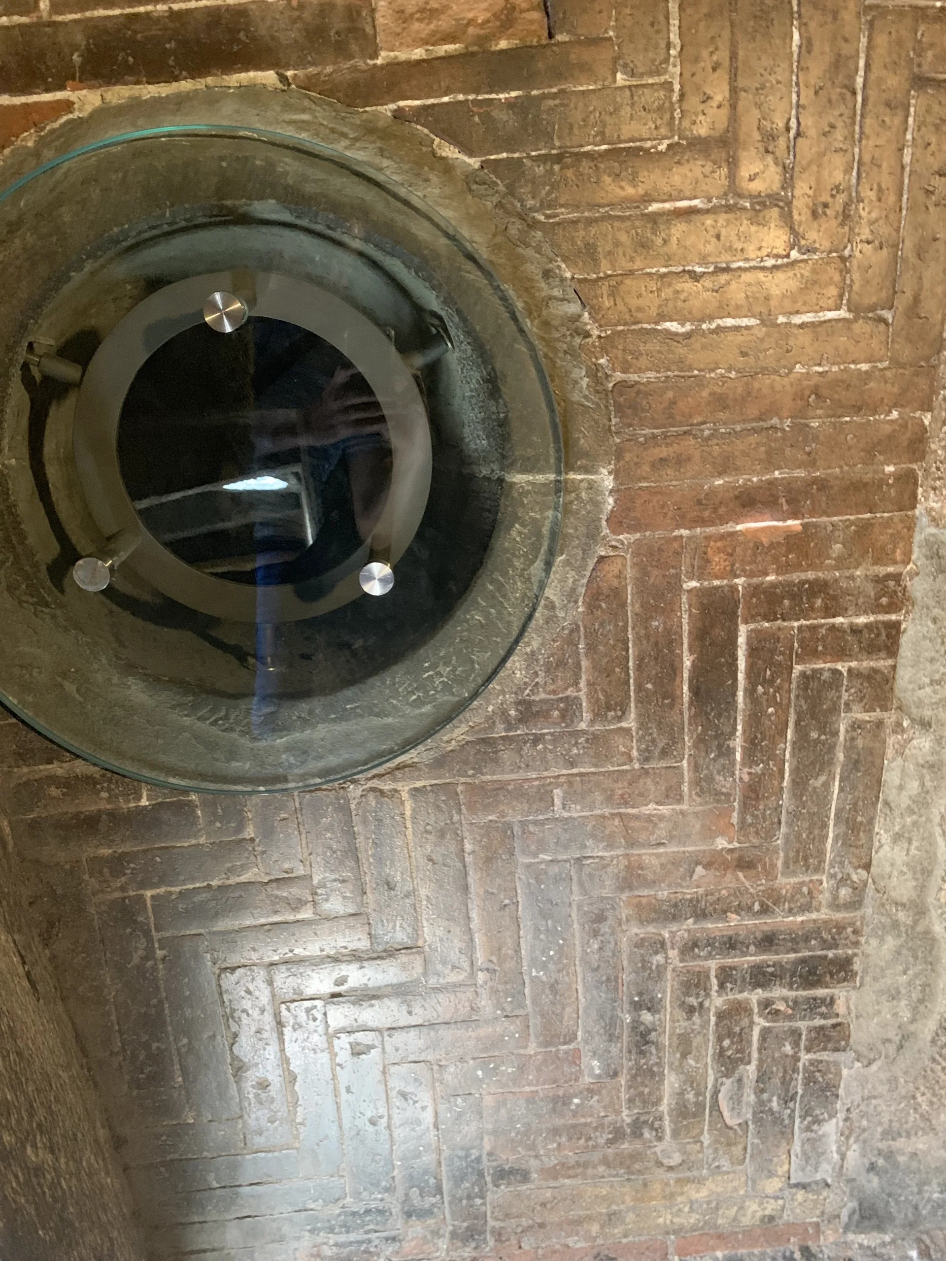 A round window set into the herringbone brickwork of Brunelleschi's dome, seen from between the shells