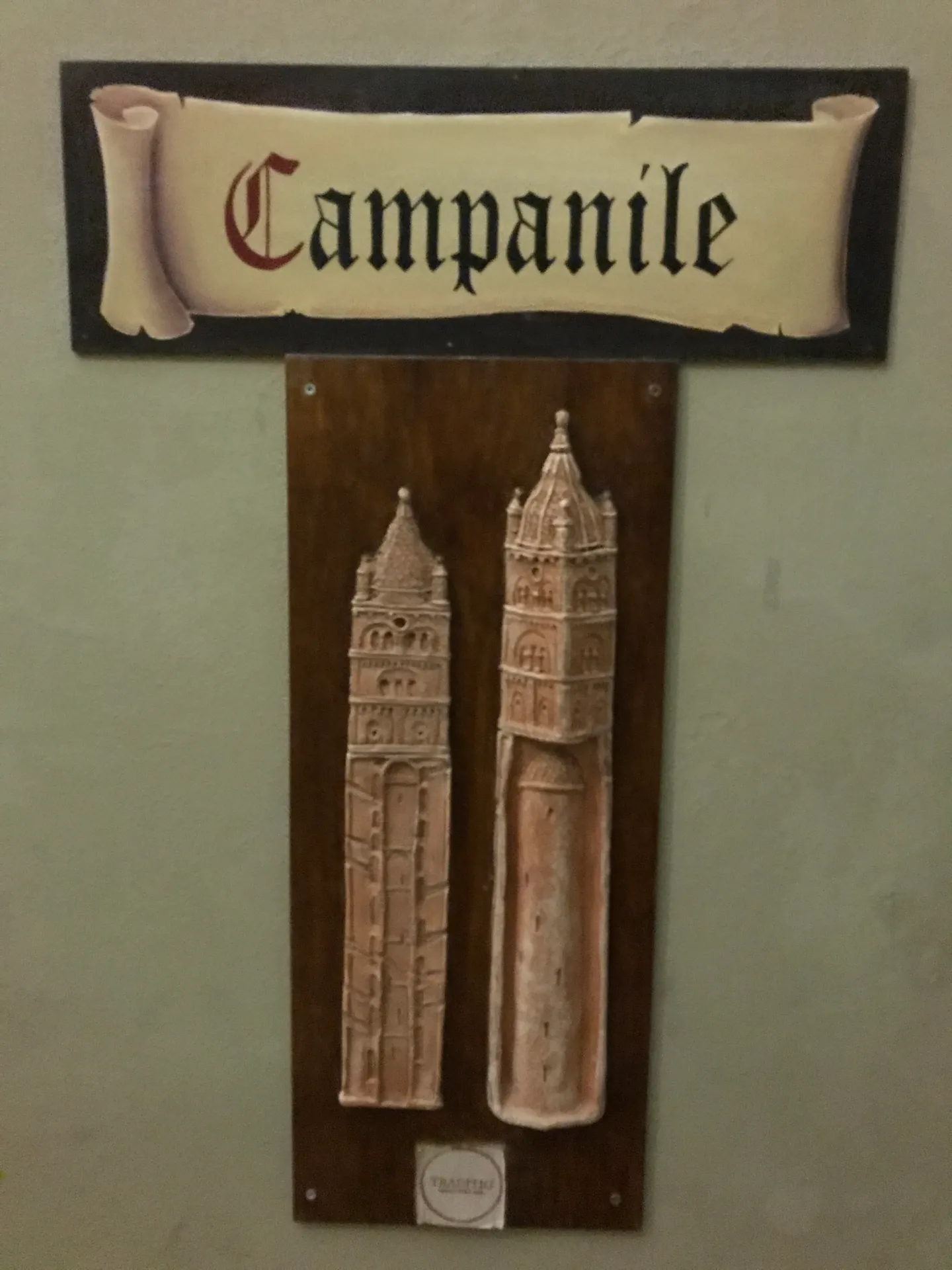 Carved stone relief showing the two bell towers of San Pietro, one inside the other.