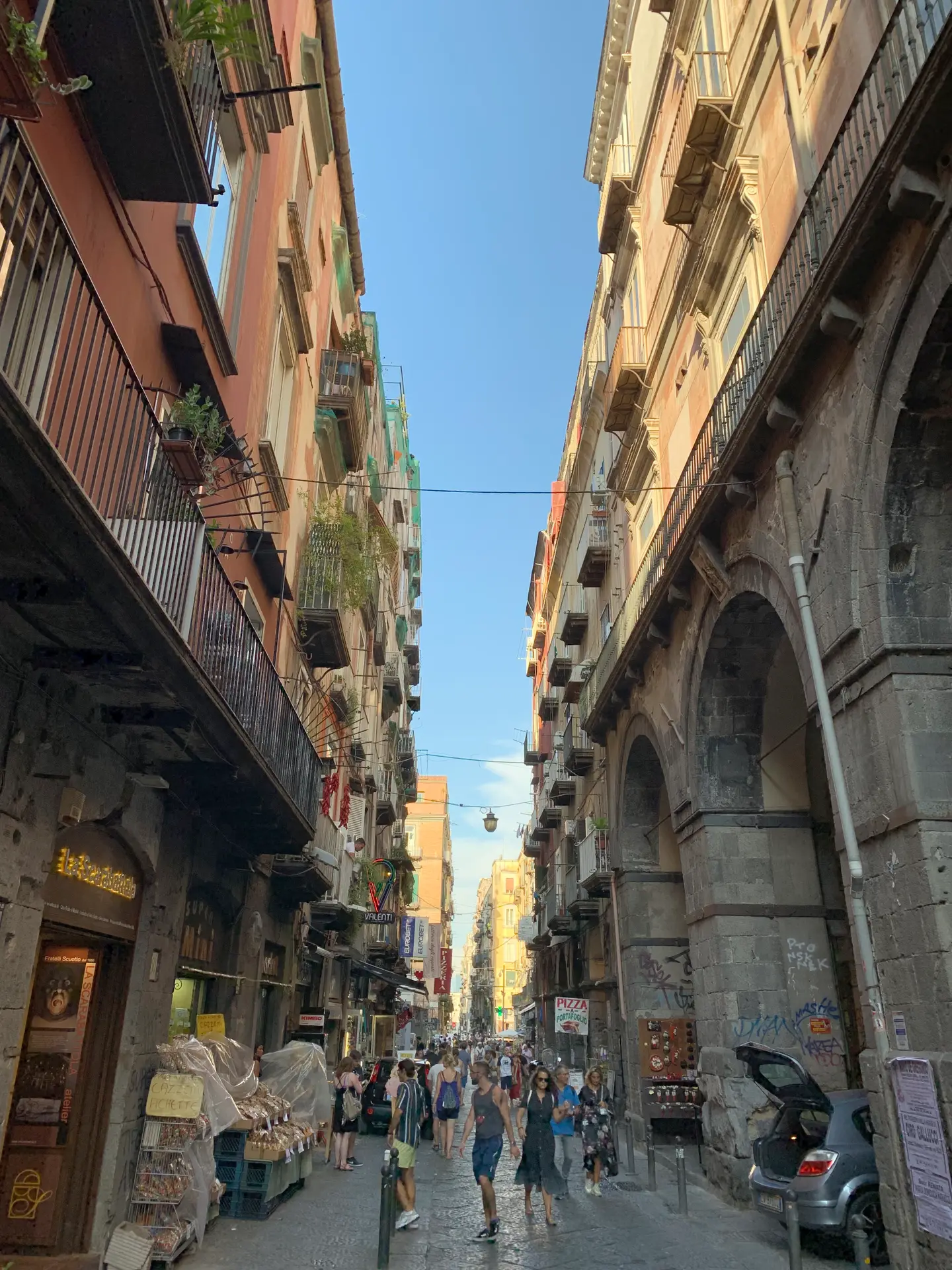 A stone arch spanning a street in the historic centre of Naples