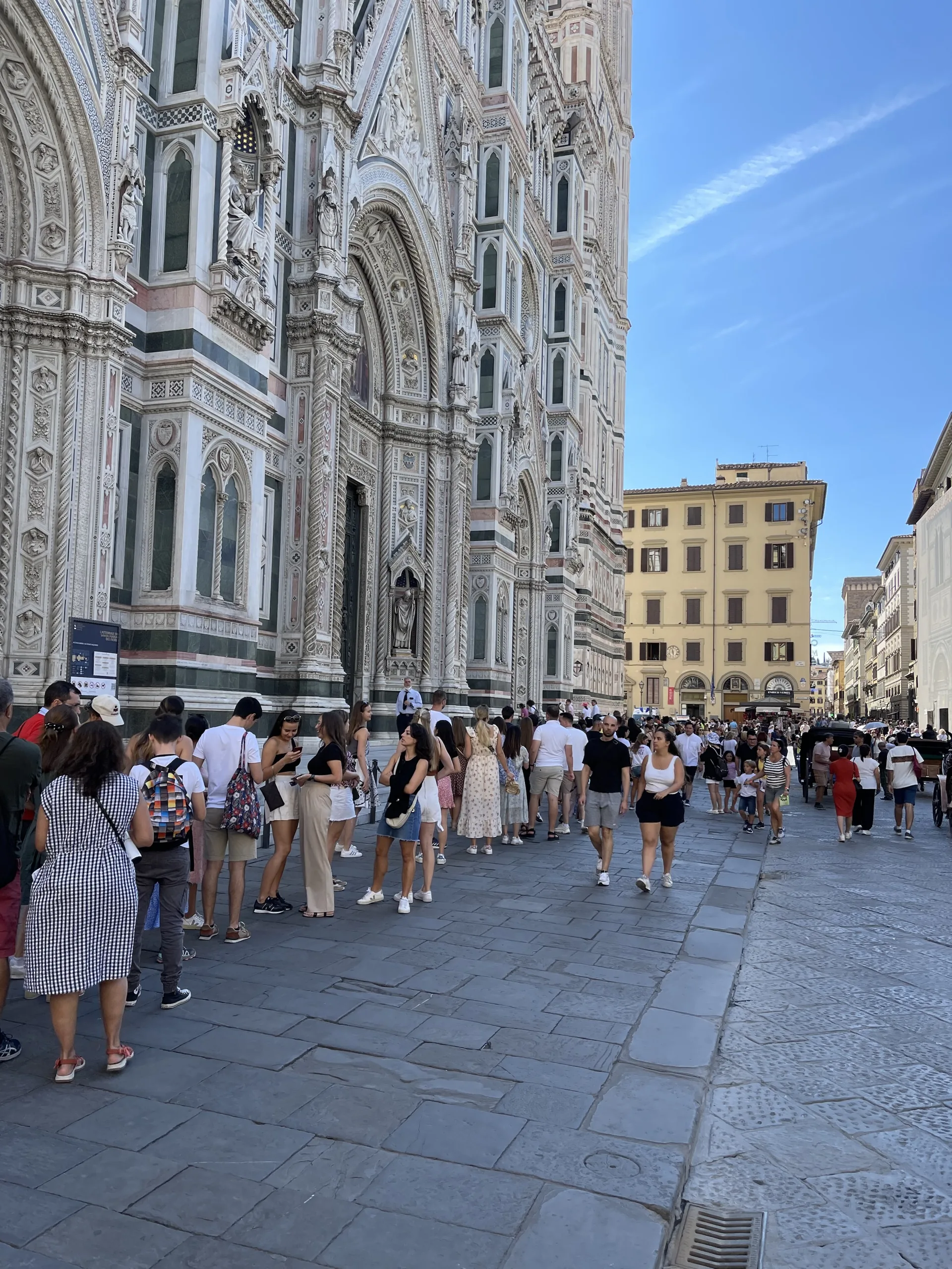 Crowds moving along the marble flank of the cathedral in Piazza del Duomo