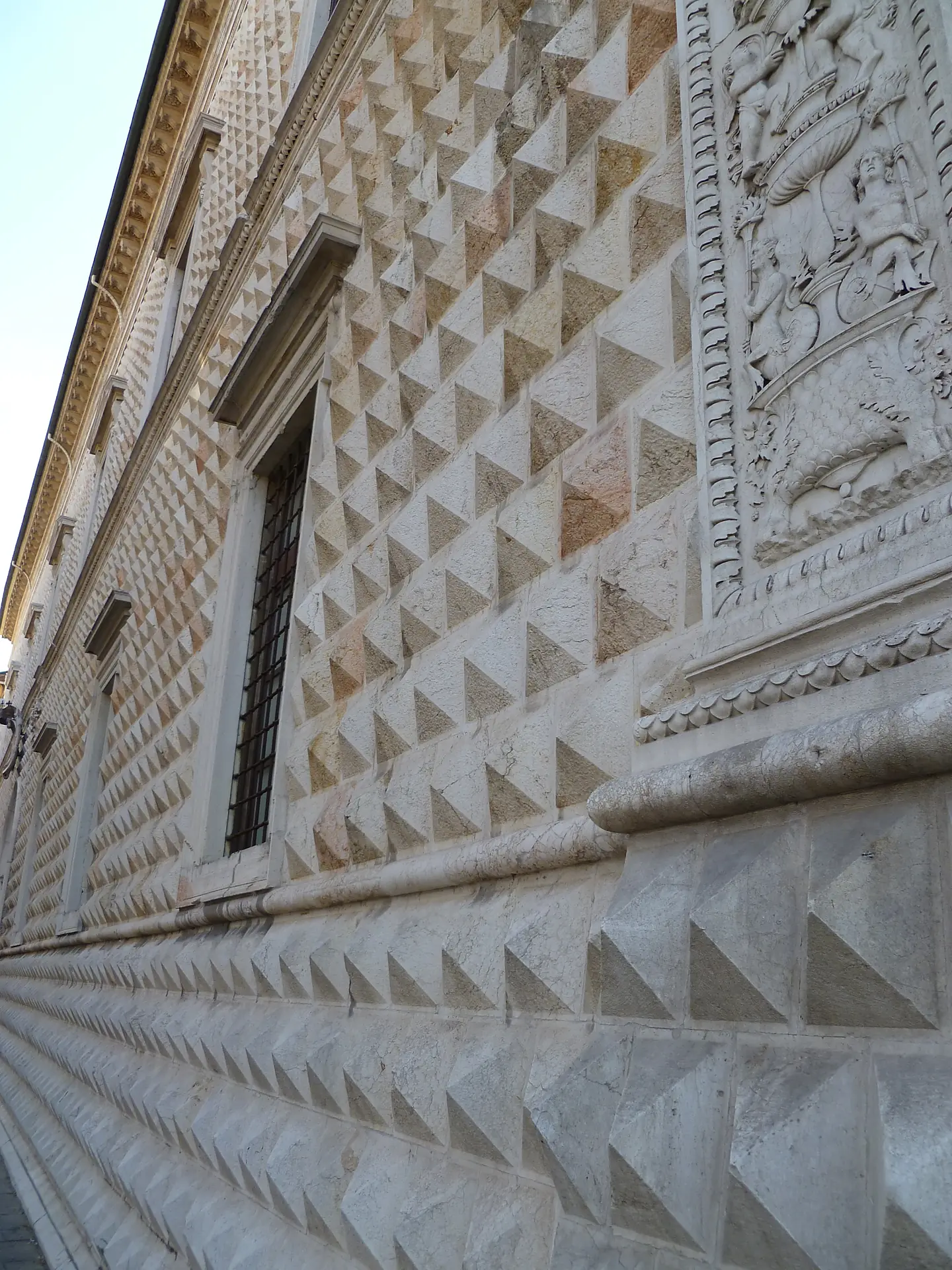 The lower diamond-cut marble blocks and sculpted base at the corner of Palazzo dei Diamanti in Ferrara.