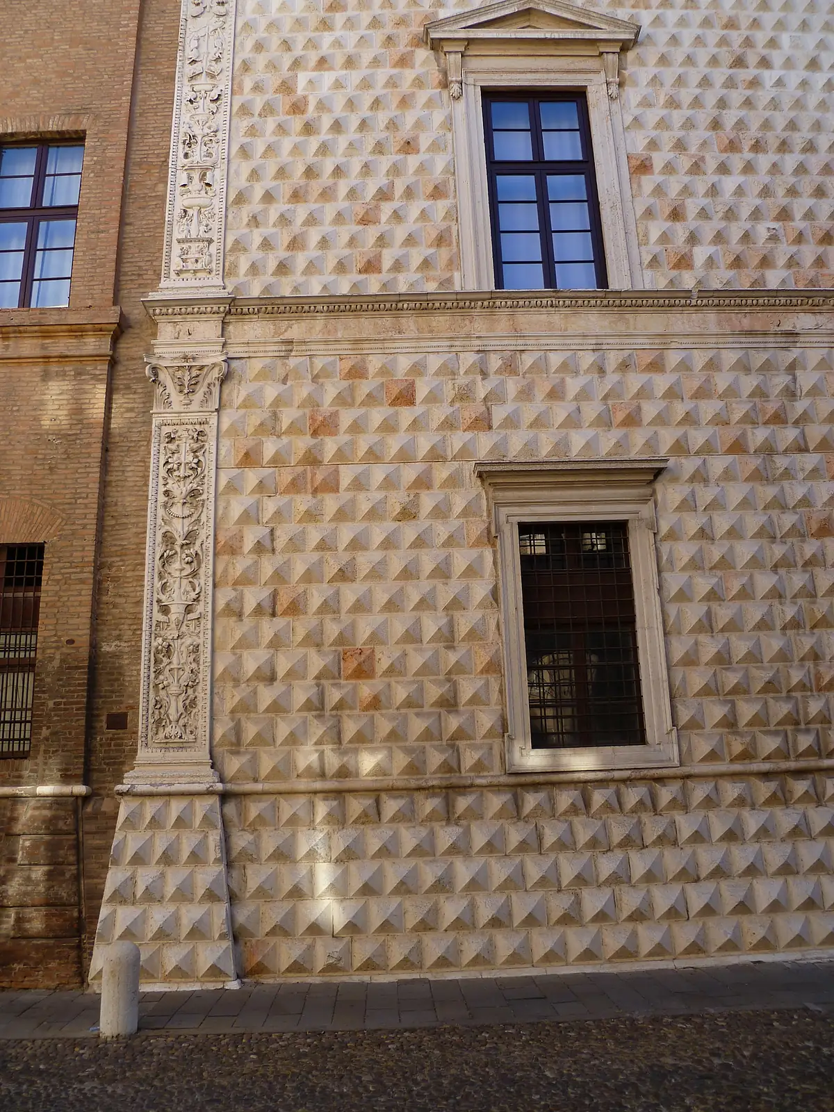 The marble corner of Palazzo dei Diamanti in Ferrara with pointed diamond blocks and a carved window.