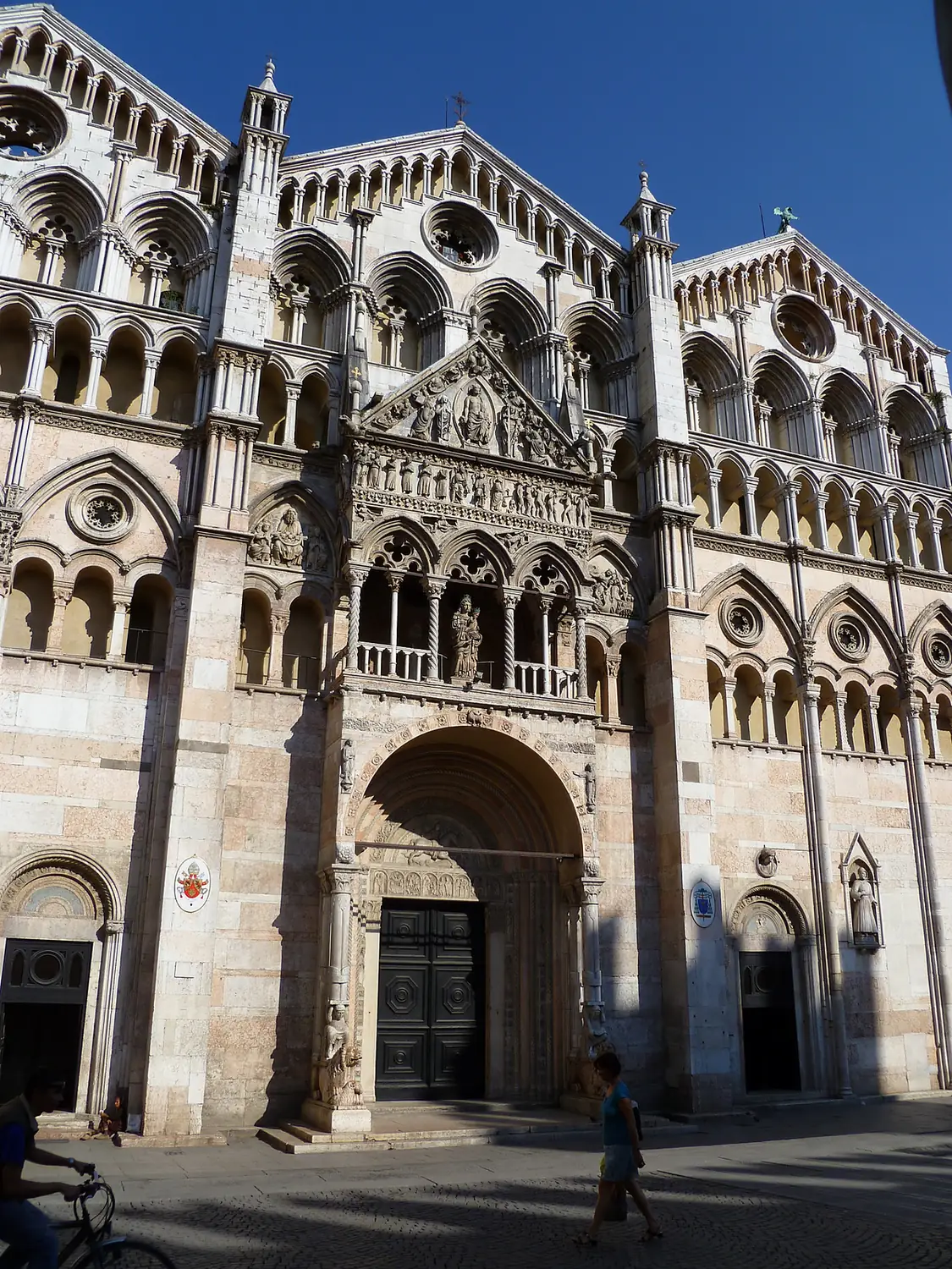 Detail of the upper Gothic arcaded gables and slender columns on the marble facade of Ferrara Cathedral.