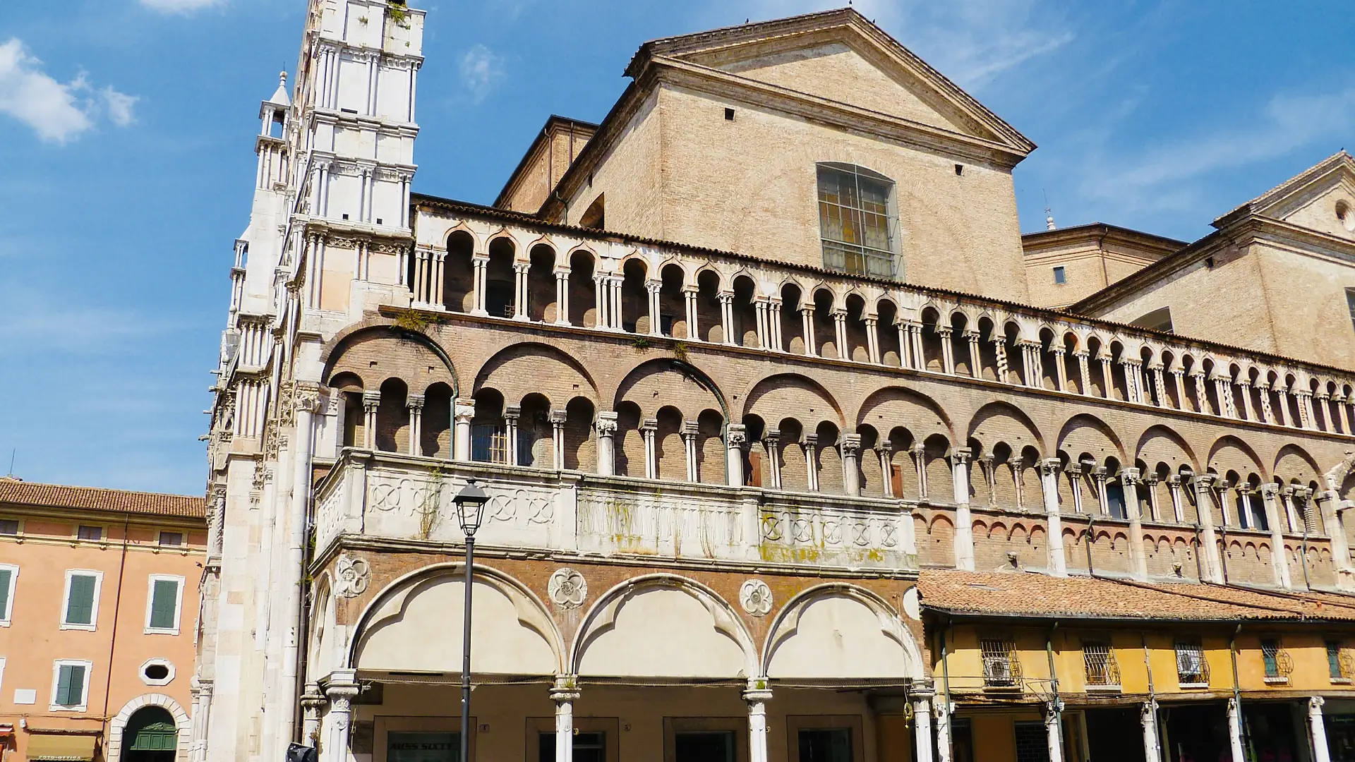 The arcaded south loggia of Ferrara Cathedral with small shops built beneath the marble gallery.