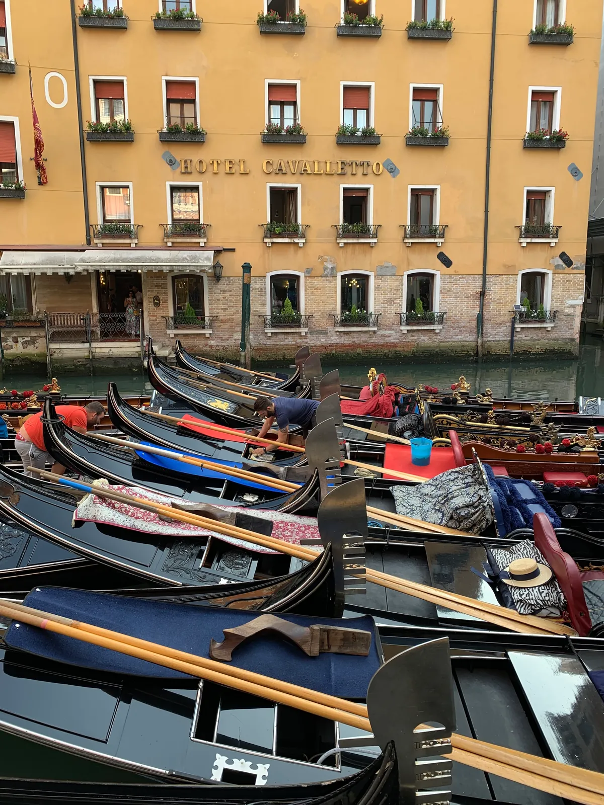 Moored gondolas with blue covers and brass fittings at a Venice mooring