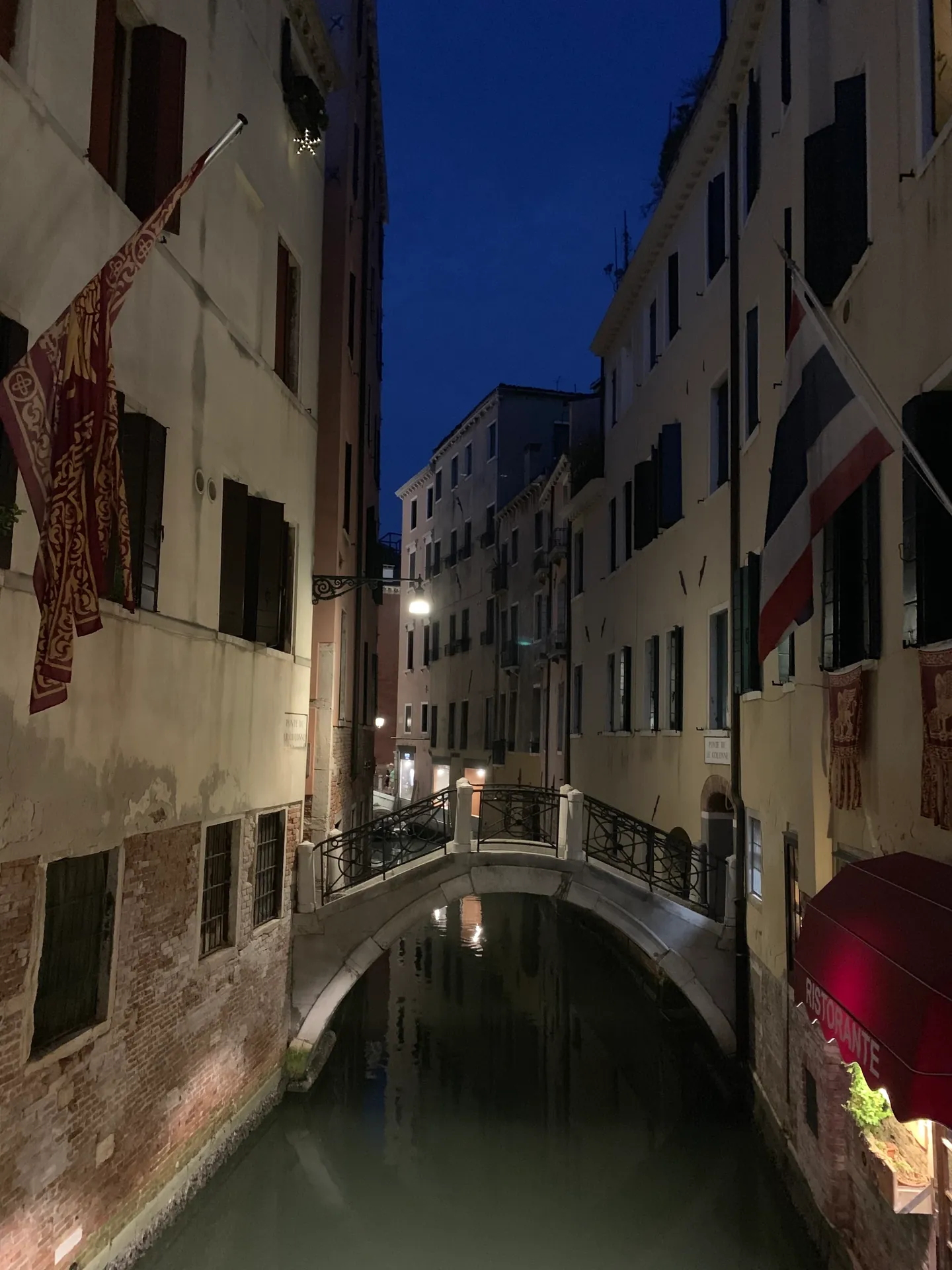 A narrow Venetian canal and a small bridge at night