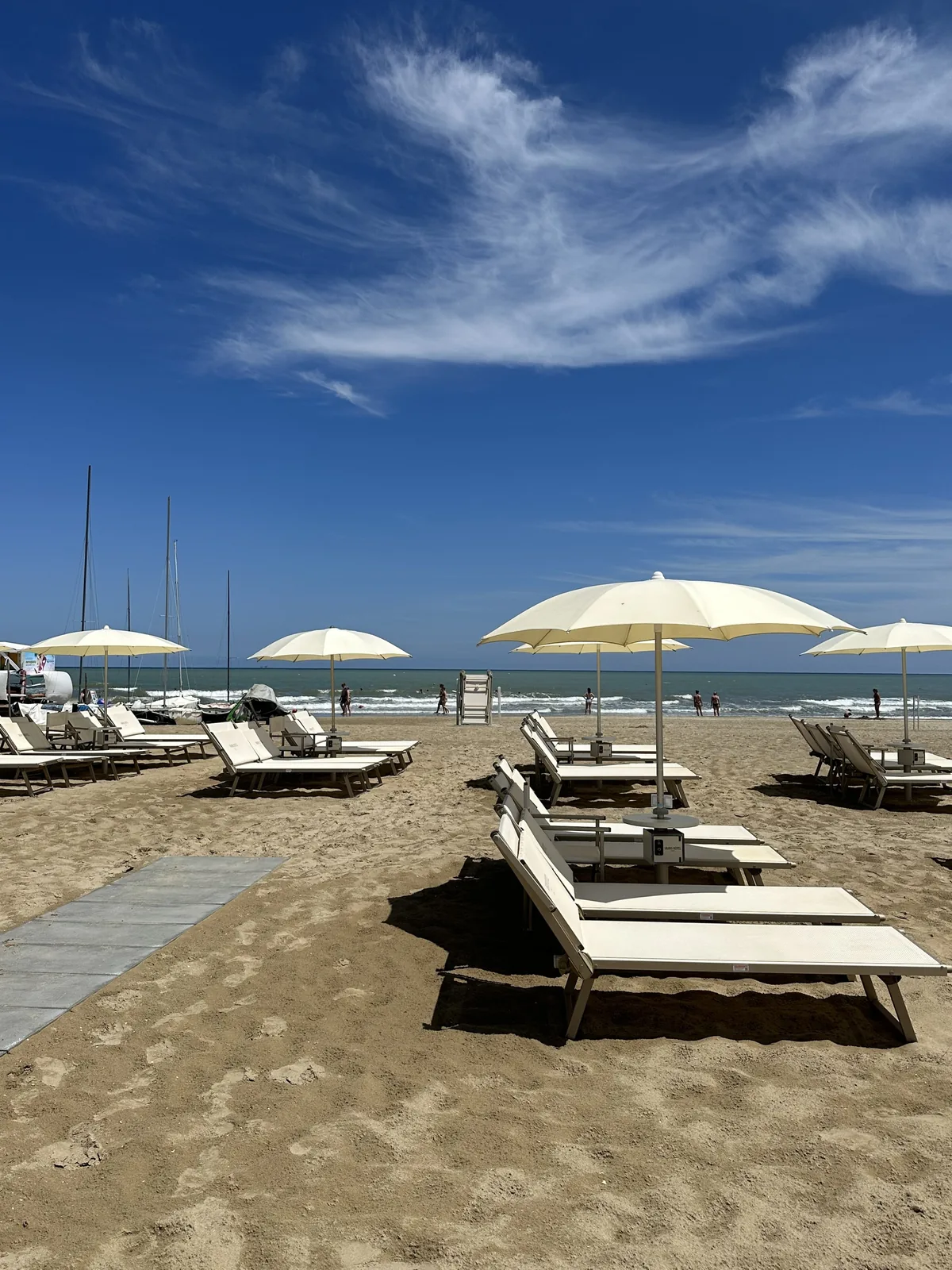 White parasols and loungers on the sand under a blue sky at the Grand Hotel Rimini beach
