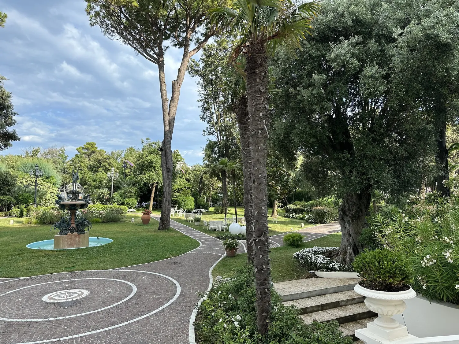 Garden path with rose beds and umbrella pines in the grounds of the Grand Hotel Rimini