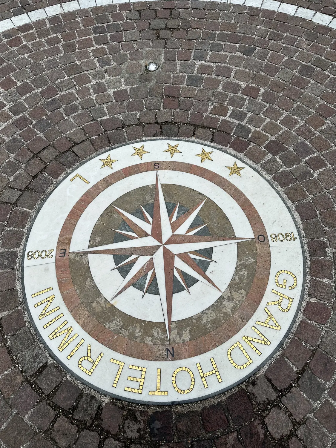 Mosaic compass rose reading Grand Hotel Rimini set into the stone floor