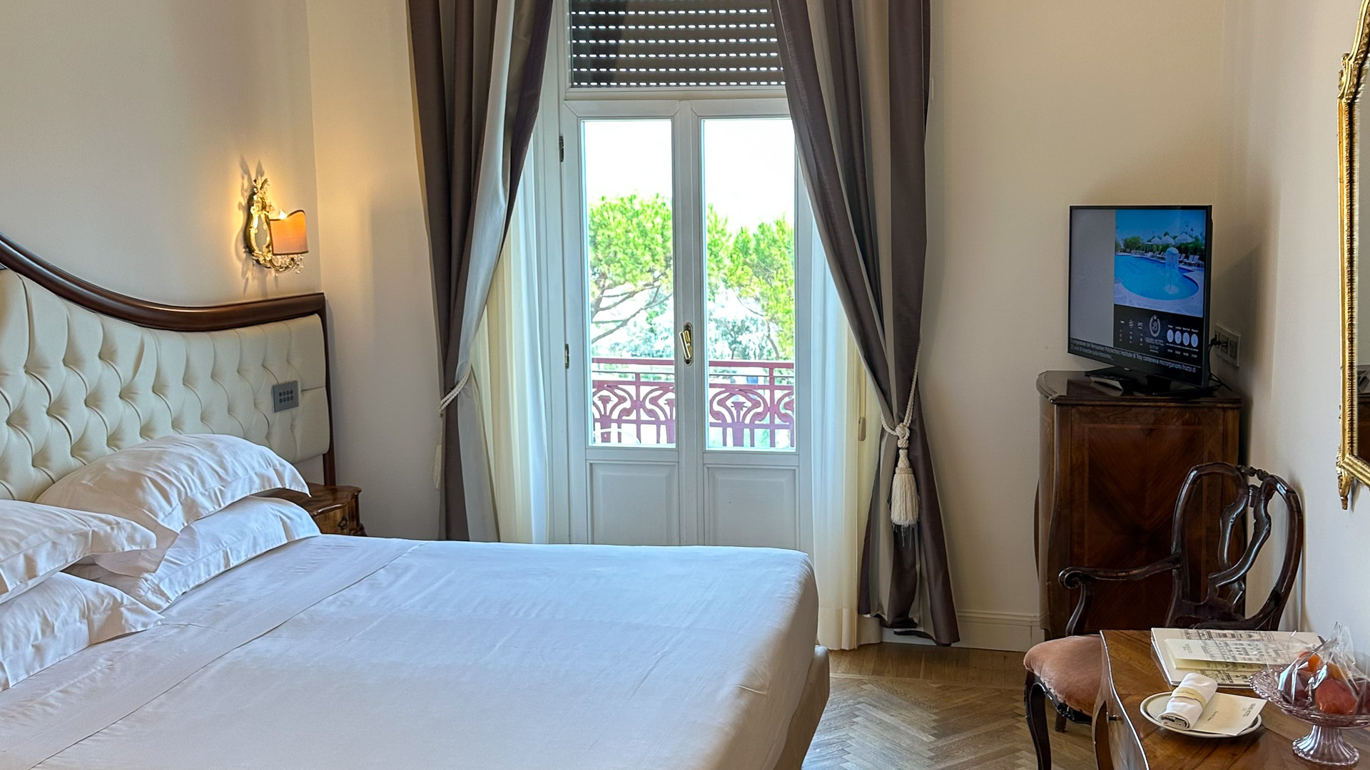 Hotel room with herringbone floor, chandelier and a balcony door at the Grand Hotel Rimini