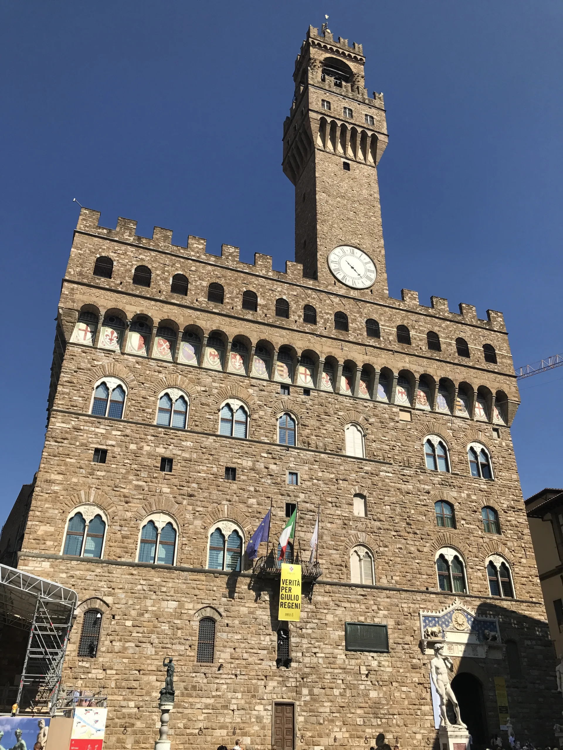 The rusticated stone facade of the Palazzo Vecchio under its crenellated gallery
