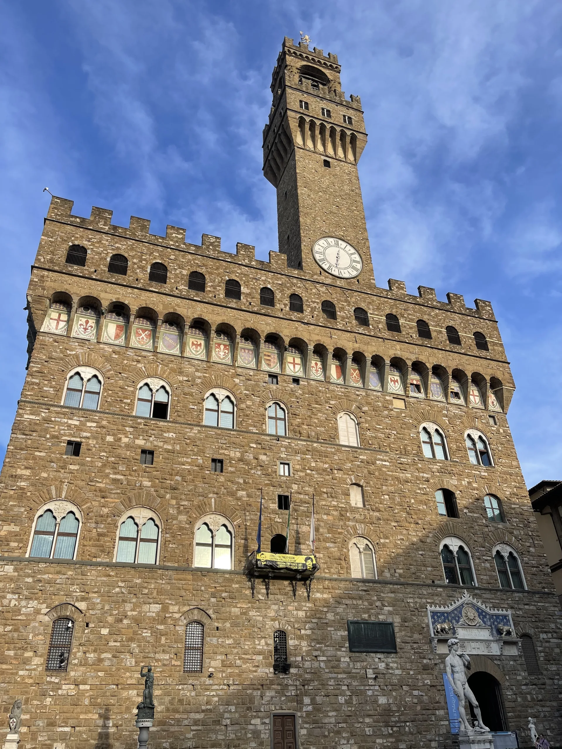 The Torre di Arnolfo rising from the Palazzo Vecchio against a blue sky
