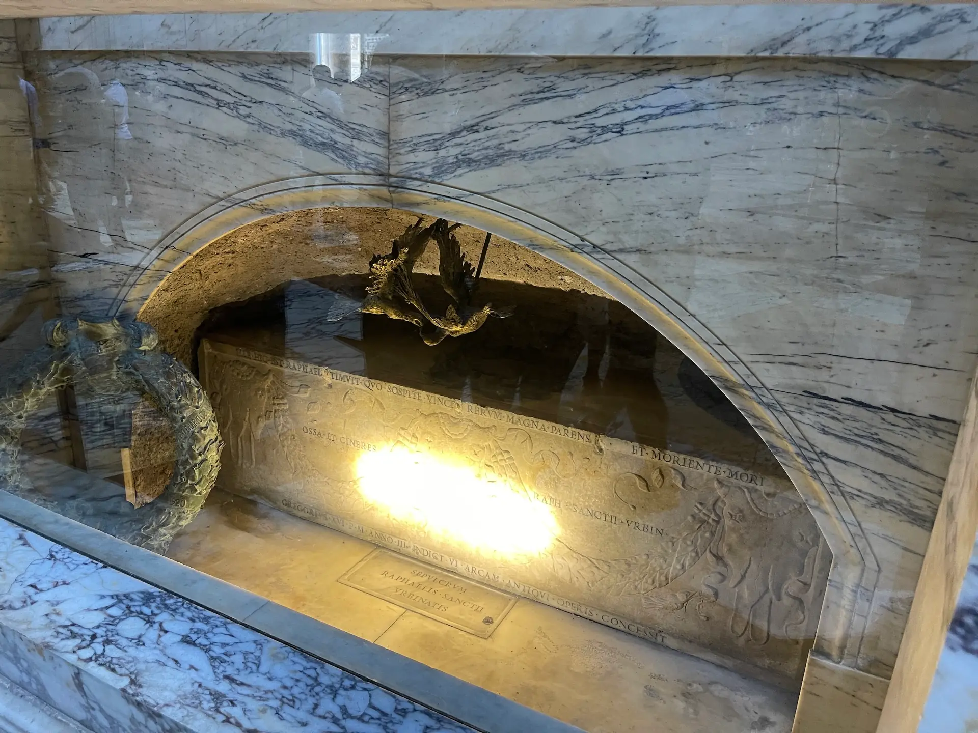The ancient sarcophagus of Raphael's tomb in the Pantheon with its lit Latin inscription