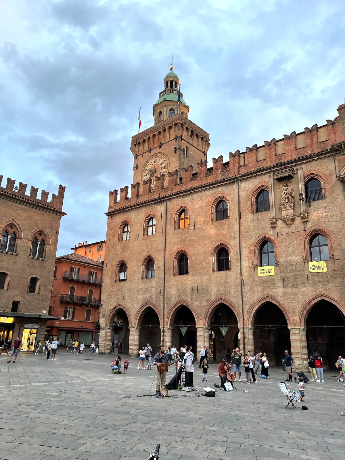 The brick facade and clock tower of Palazzo d'Accursio on Piazza Maggiore.