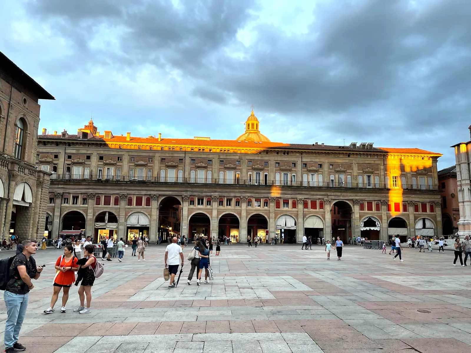 Piazza Maggiore at golden hour with San Petronio and the glowing Banchi arcade.