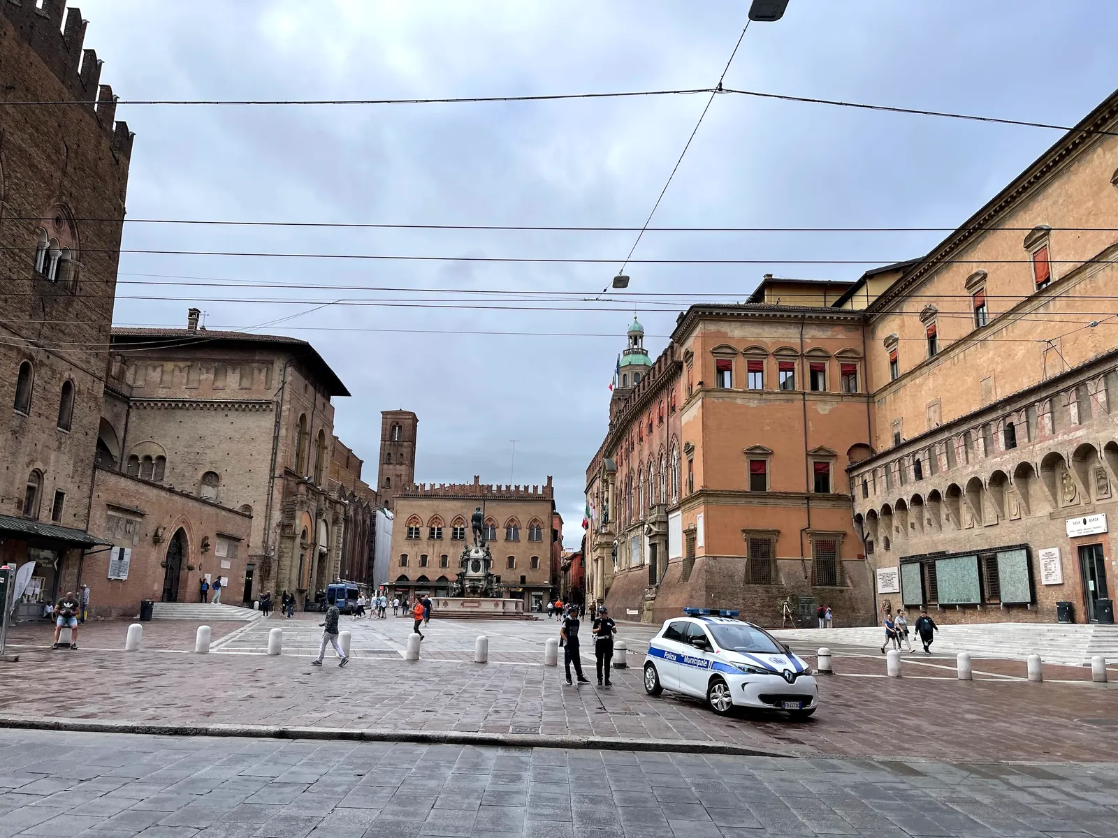 Wide view of Piazza Maggiore in Bologna ringed by medieval palaces.