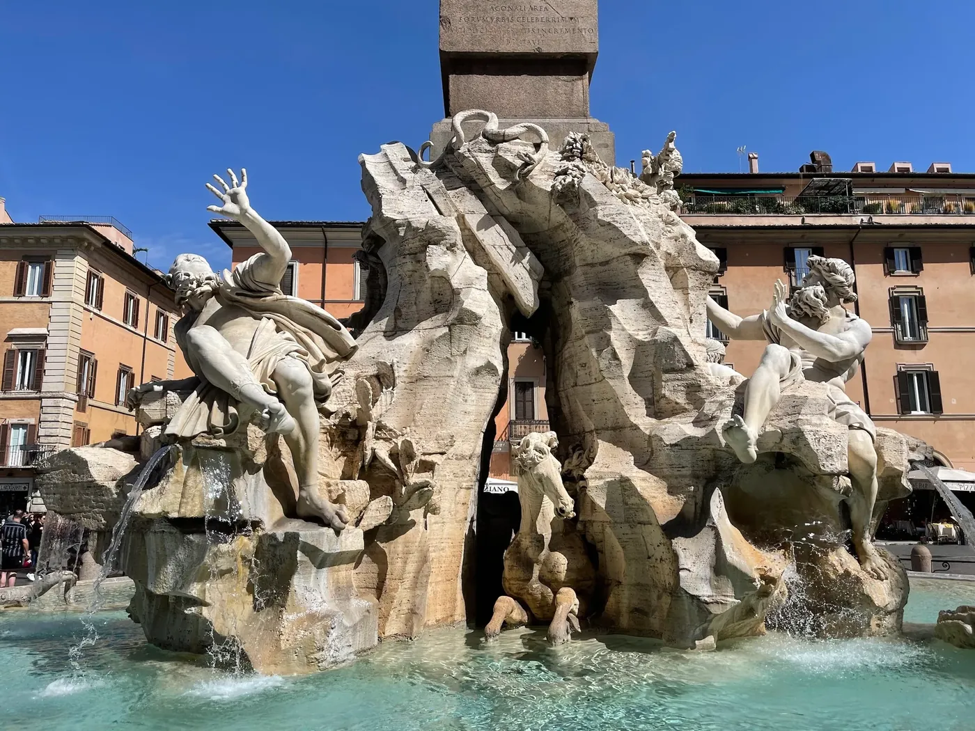 Two river god statues on the sunlit travertine crag of the Four Rivers fountain