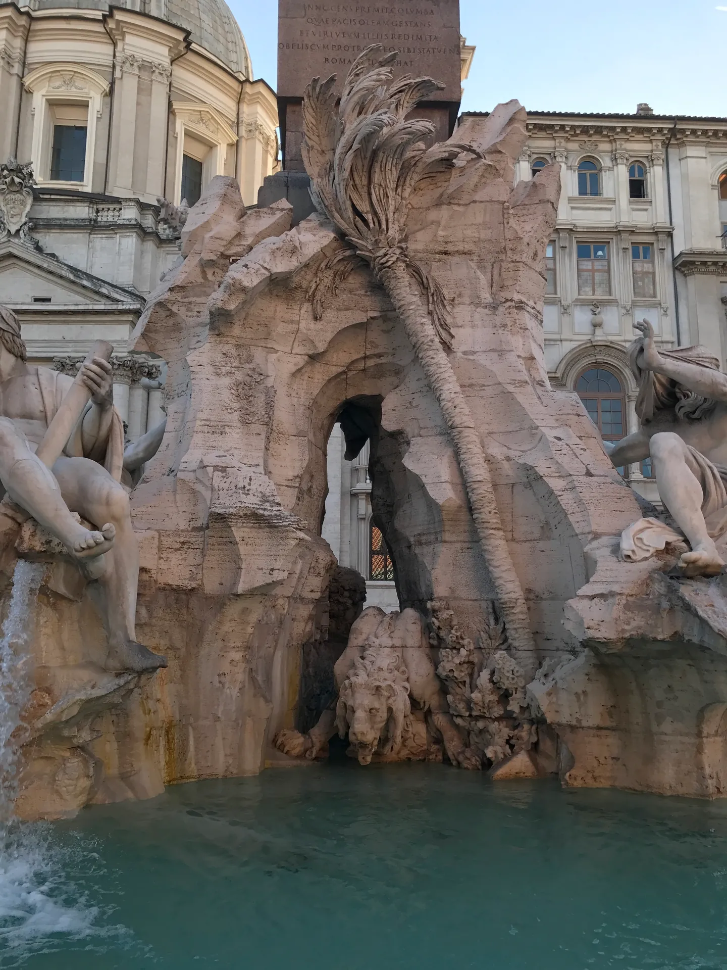 Carved lion drinking beneath a stone palm tree on the Fountain of the Four Rivers