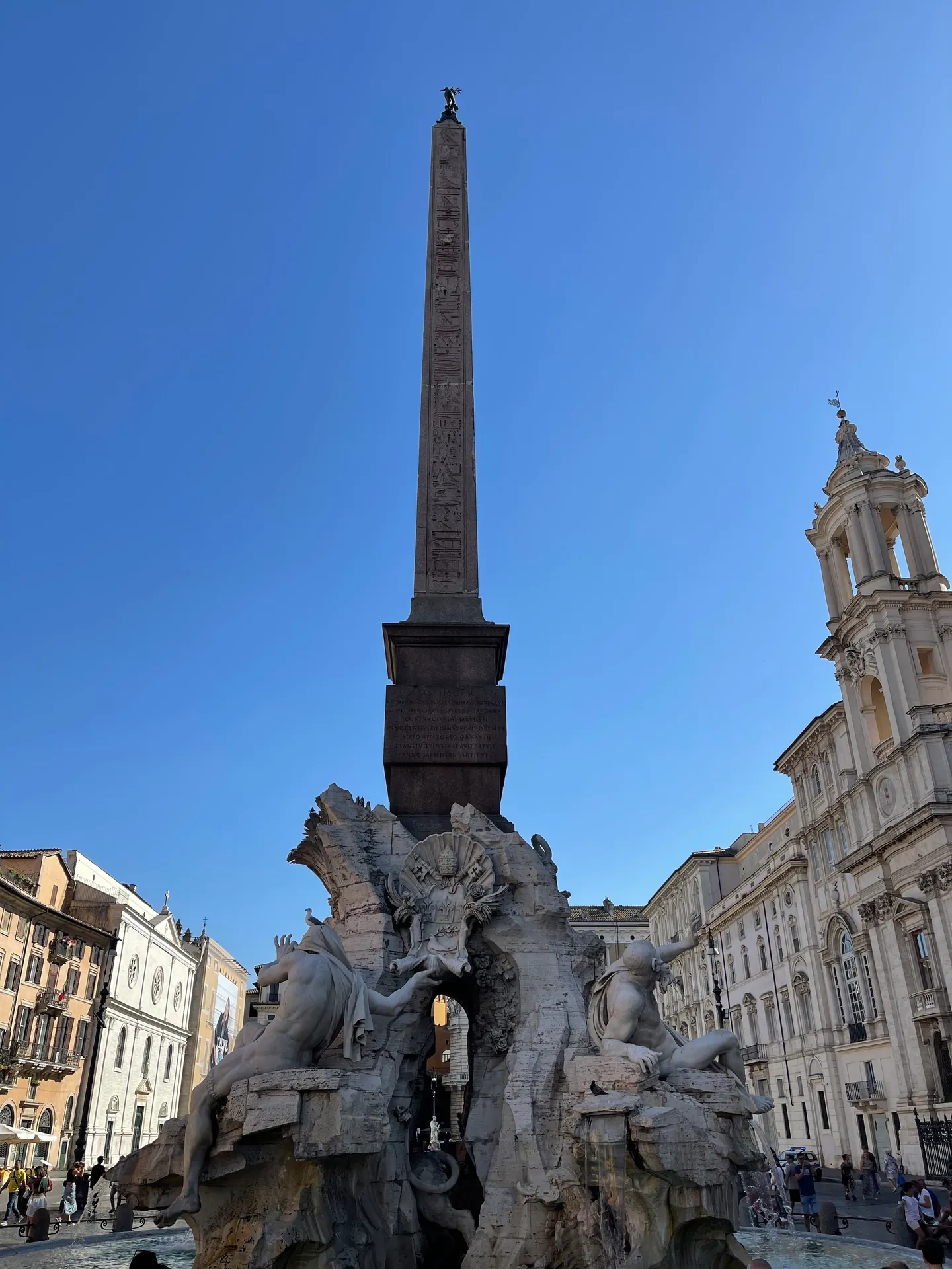 Obelisk of Domitian rising from the Fountain of the Four Rivers against a blue sky