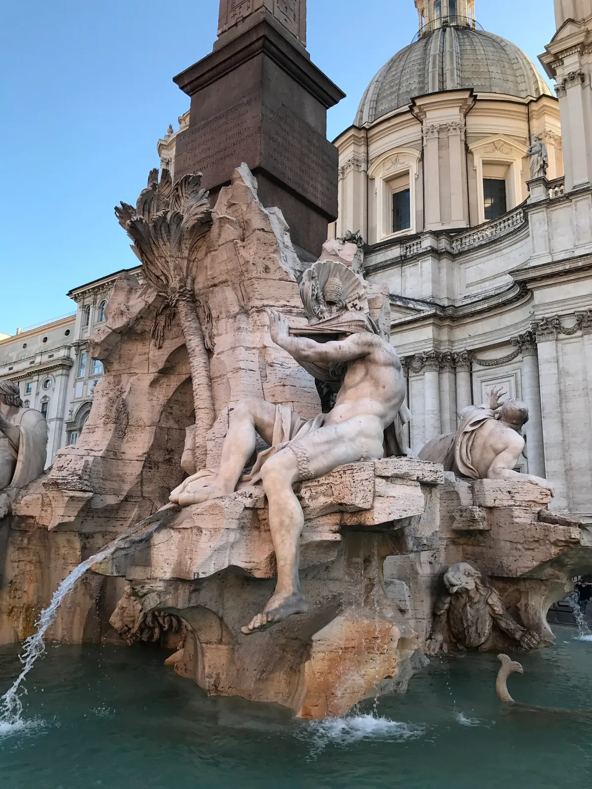 River god statue on the Four Rivers fountain with the dome of Sant'Agnese in Agone behind