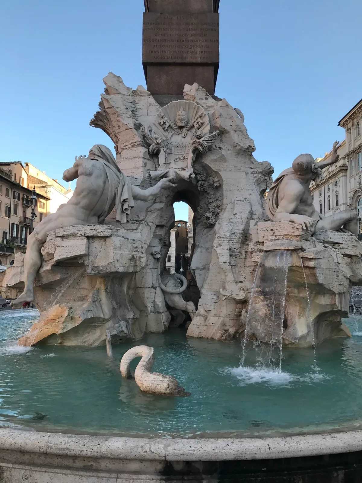 Stone sea serpent curling out of the water below the Four Rivers fountain statues