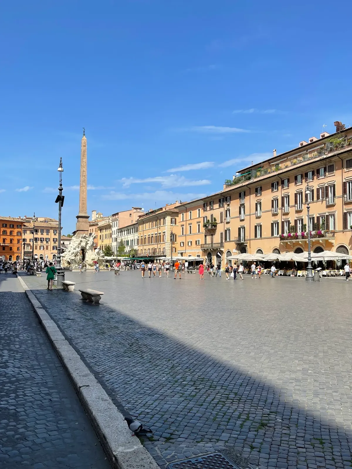 Long view of Piazza Navona's open cobblestones with the Four Rivers obelisk in the distance