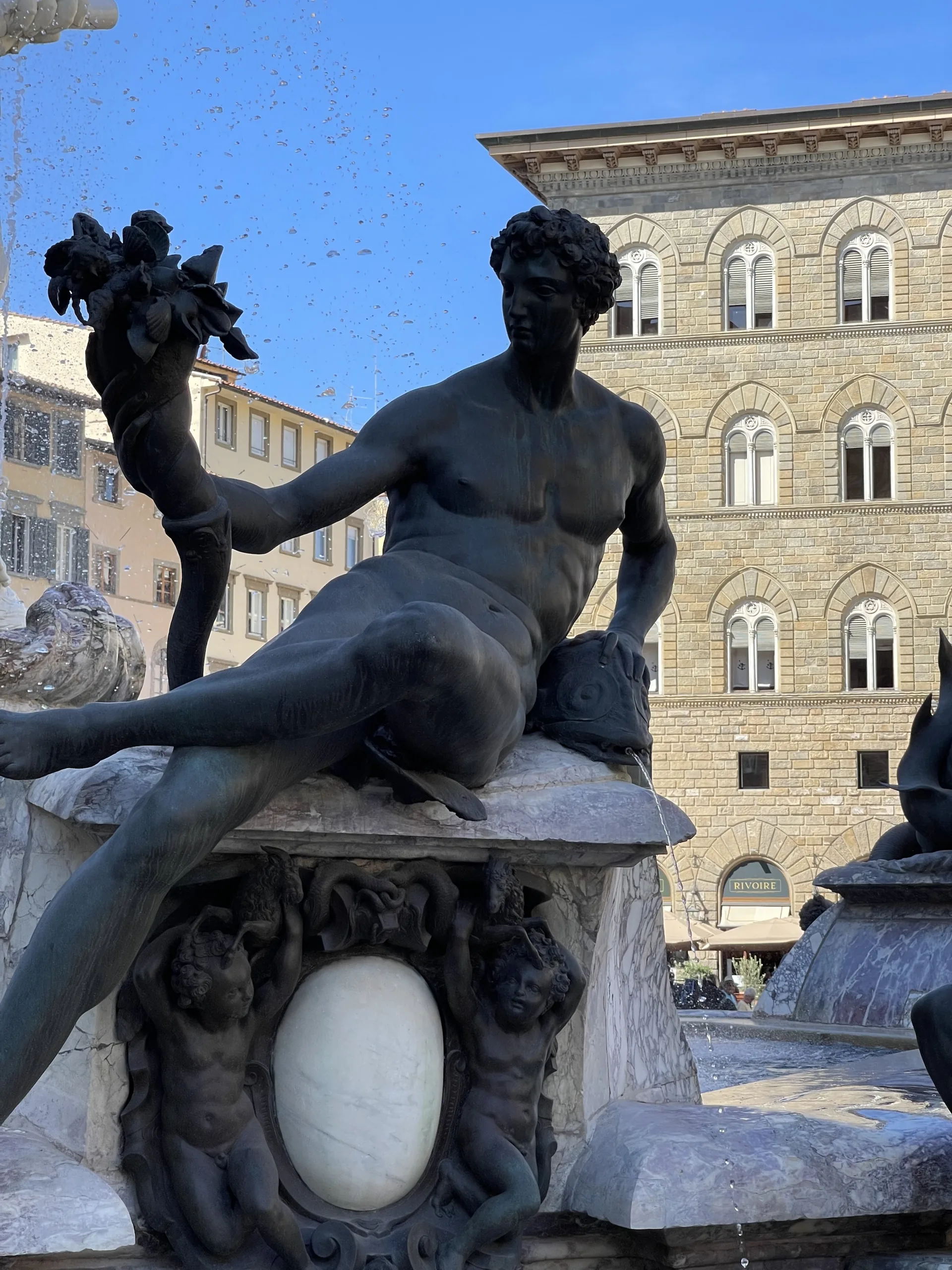 A reclining bronze figure on the edge of the Neptune fountain basin