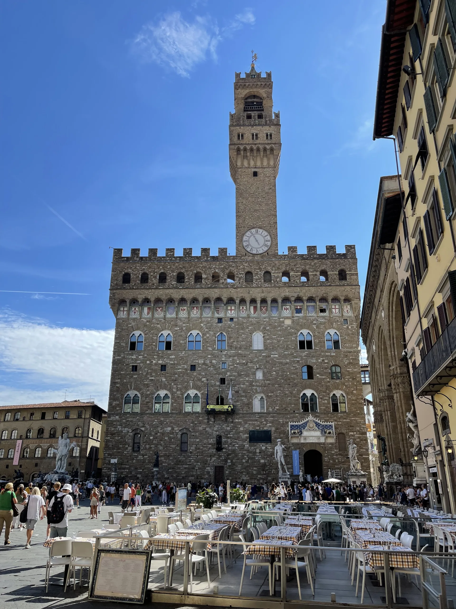 Cafe tables set out on Piazza della Signoria below the tower of the Palazzo Vecchio