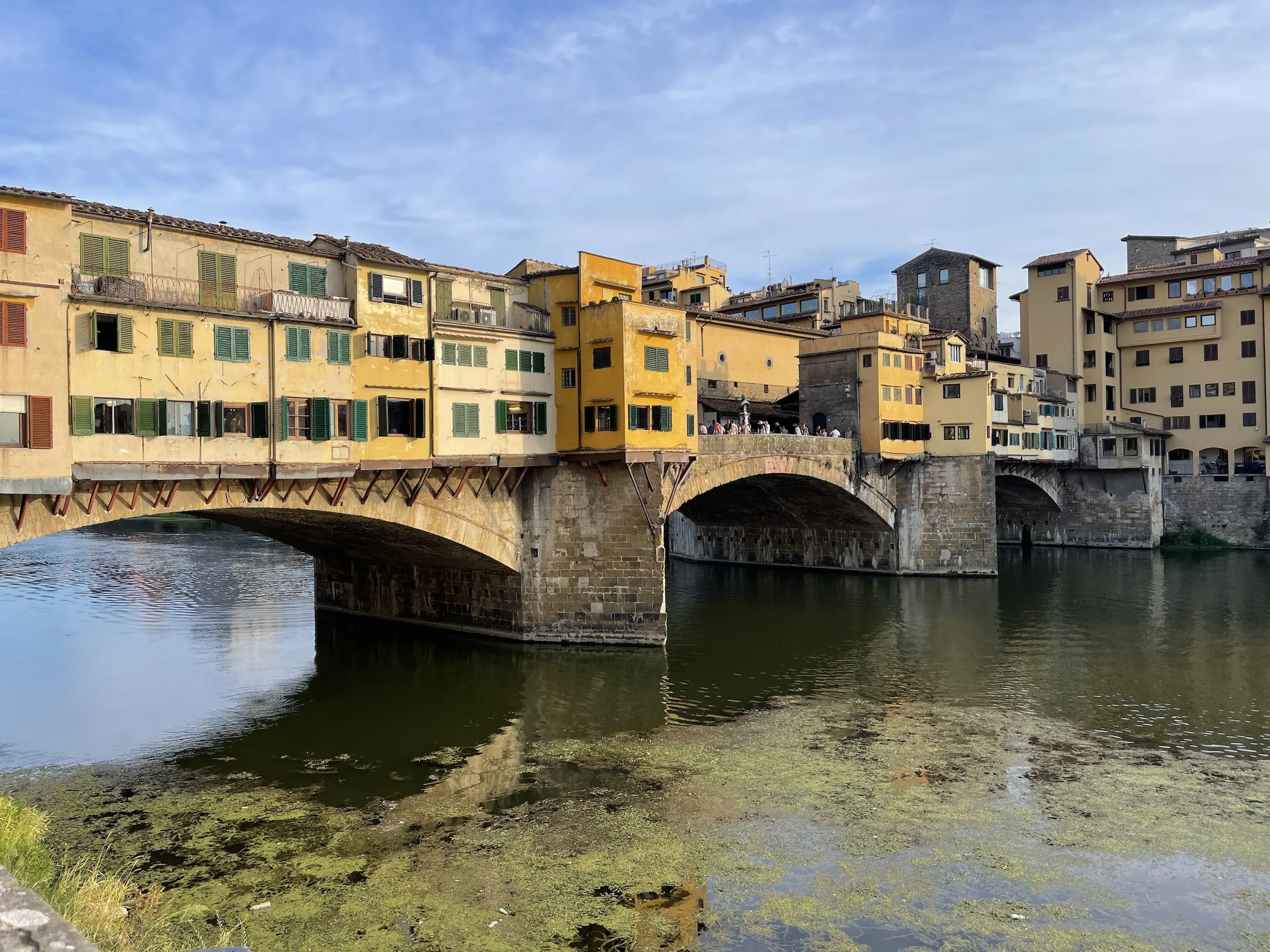 The Ponte Vecchio reflected in the still green water of the Arno