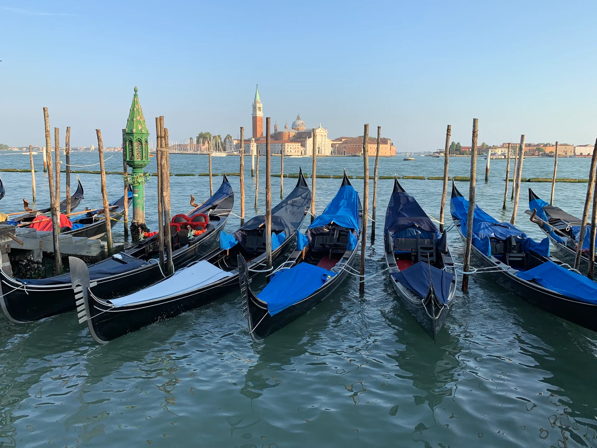 Gondolas moored on the waterfront with San Giorgio Maggiore across the basin in warm light