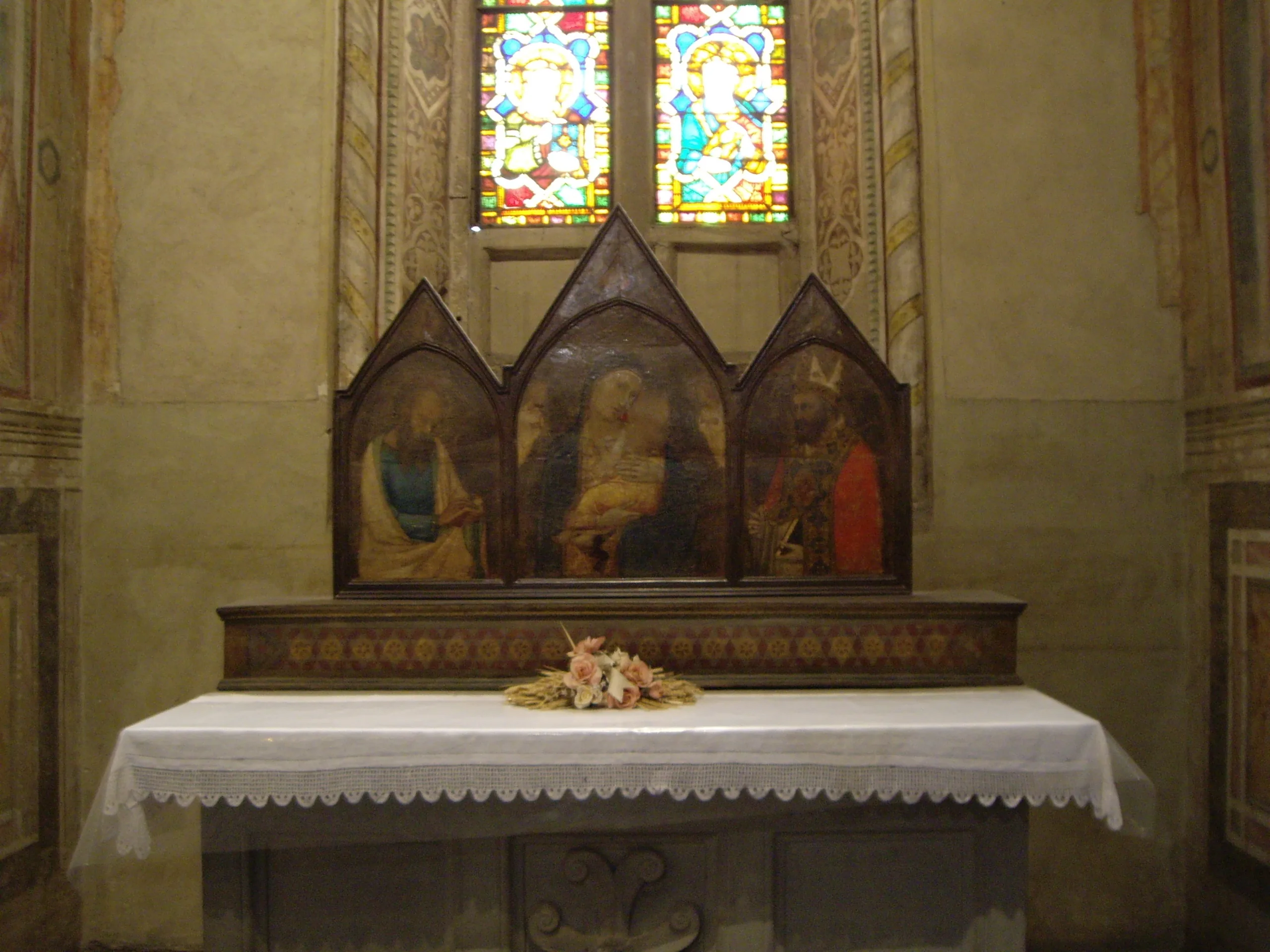 A side altar in Santa Croce with a painted triptych below stained glass