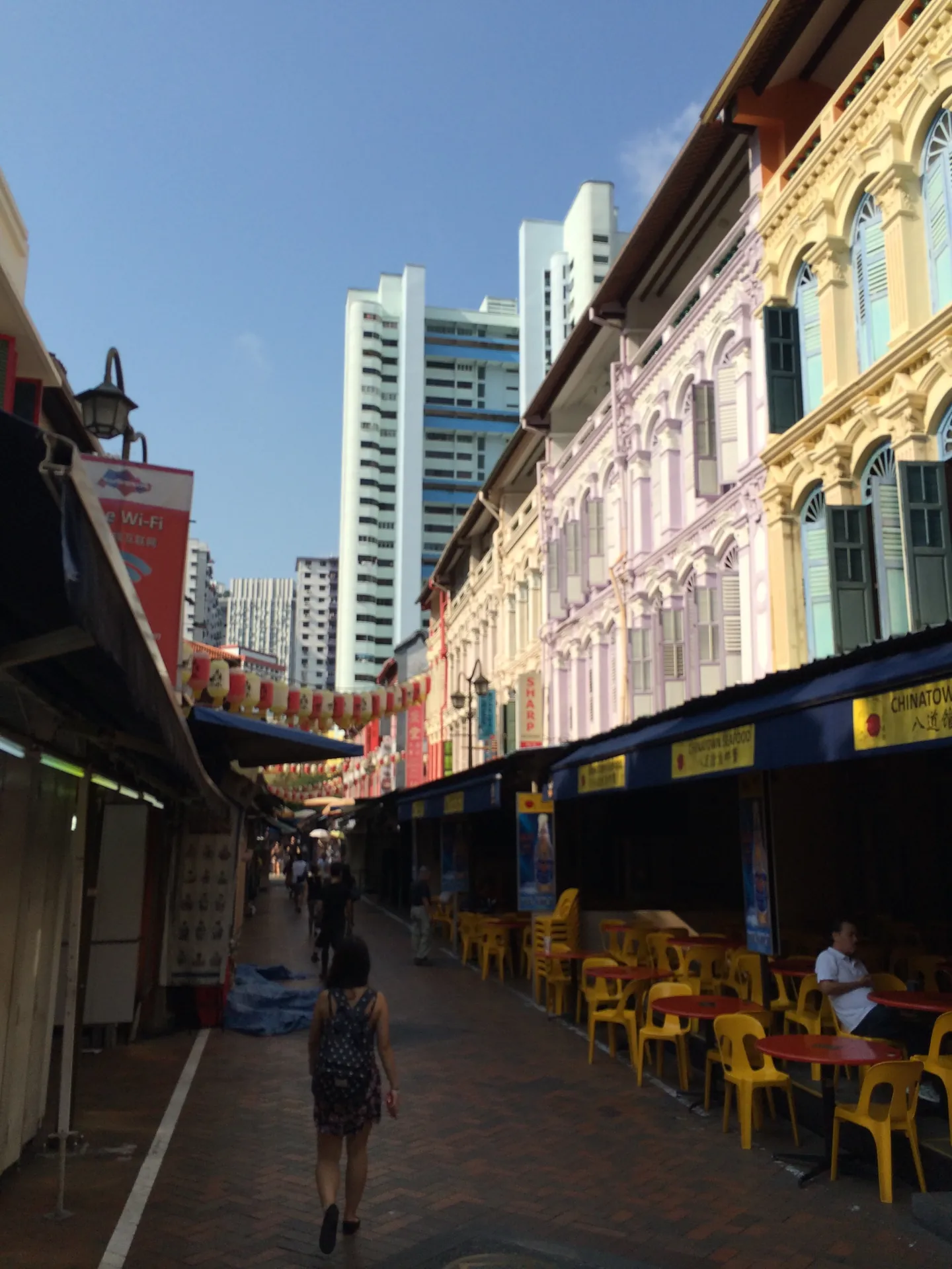 A Chinatown food street lined with red stools and shophouses