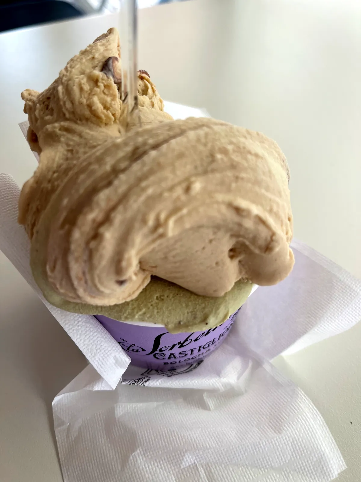 A cup of caramel cream gelato over pistachio from La Sorbetteria Castiglione.