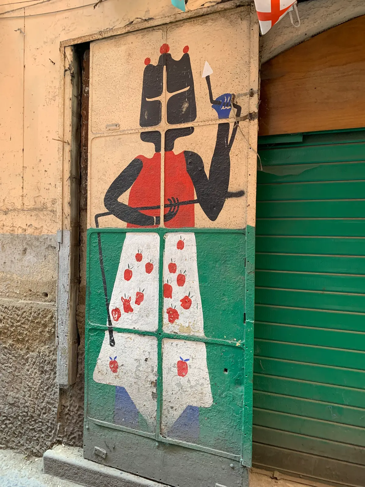 A painted figure with playing cards on a green shop shutter, Spanish Quarter, Naples