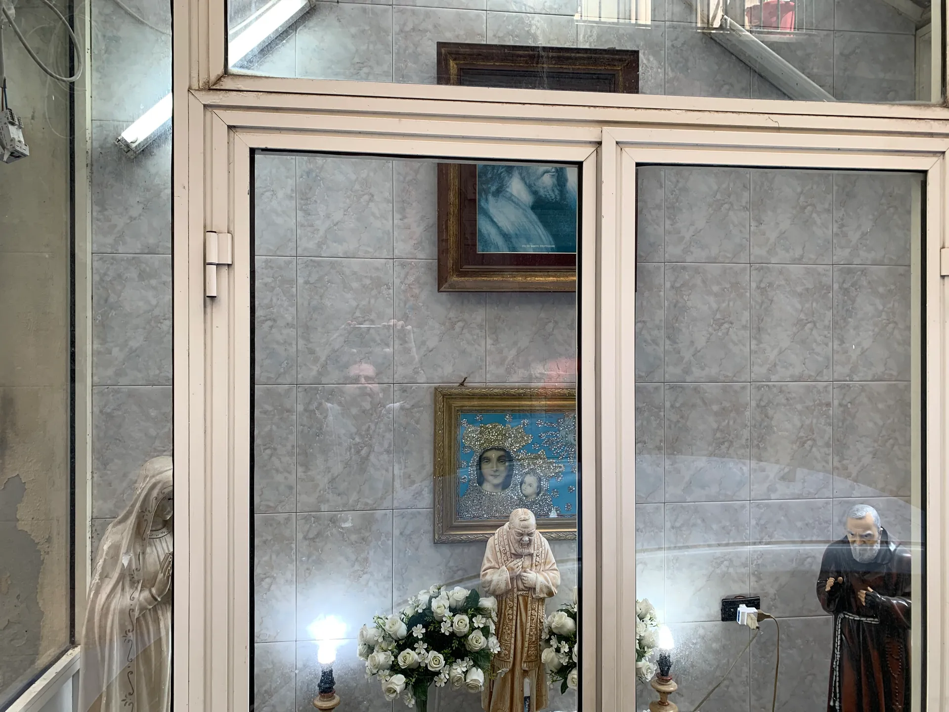 A glazed wall shrine with statues, flowers and candles in the Spanish Quarter, Naples
