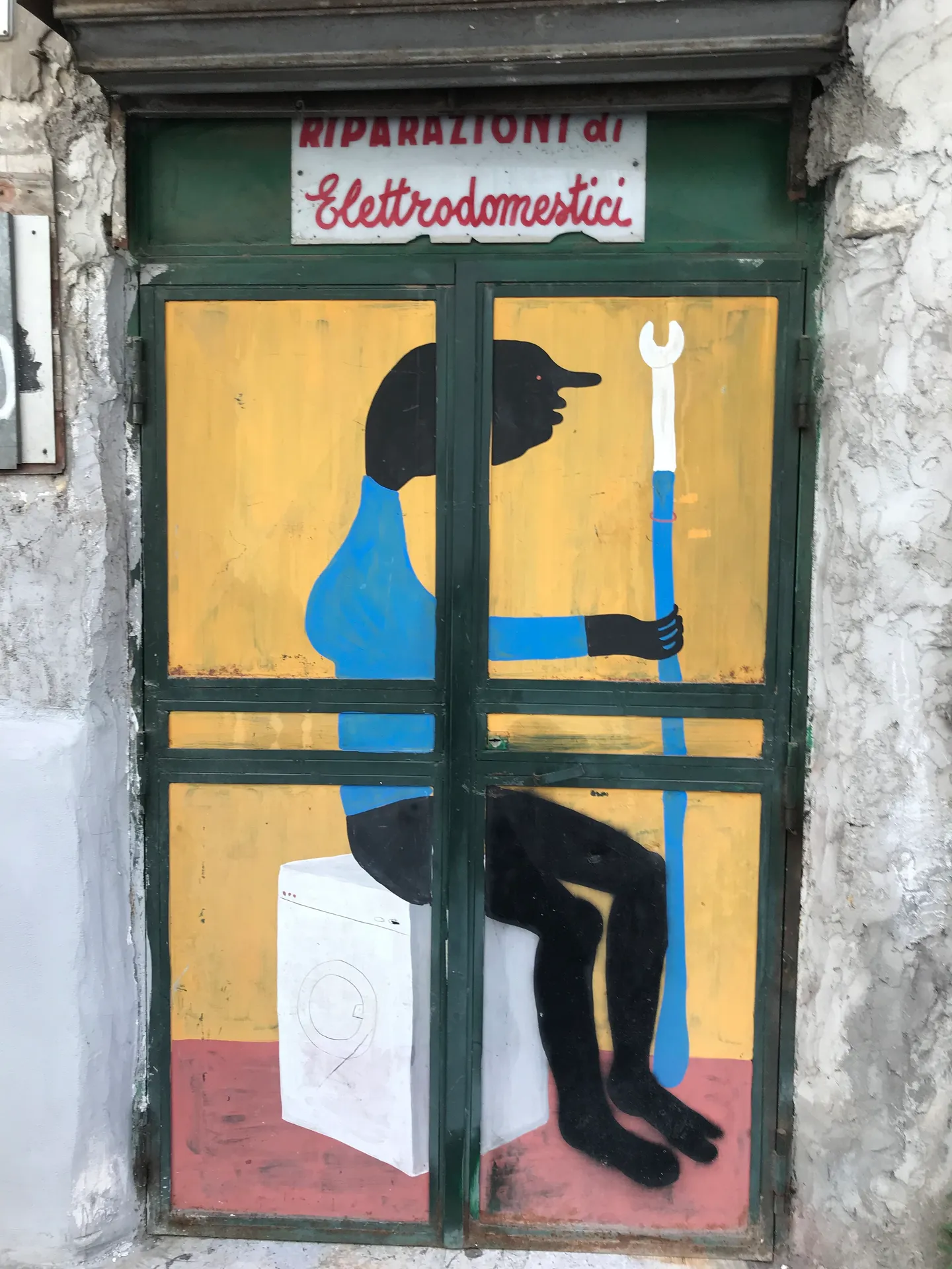 A painted figure on the shutter of a repair shop in the Spanish Quarter, Naples