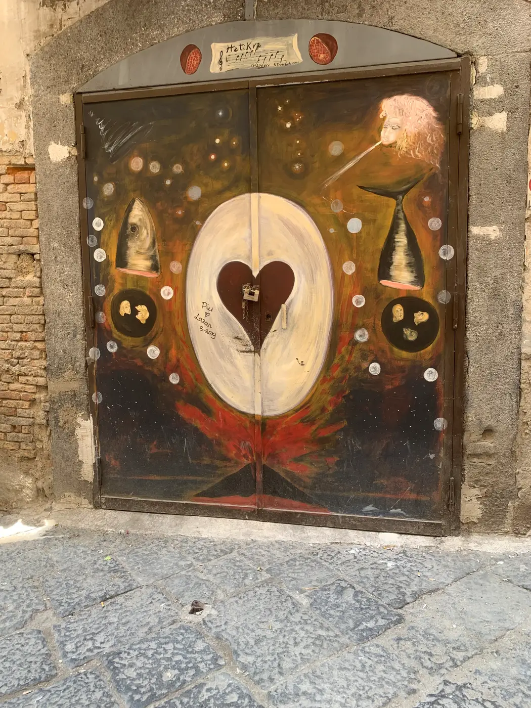 A painted heart and scales across an old double door in the Spanish Quarter, Naples