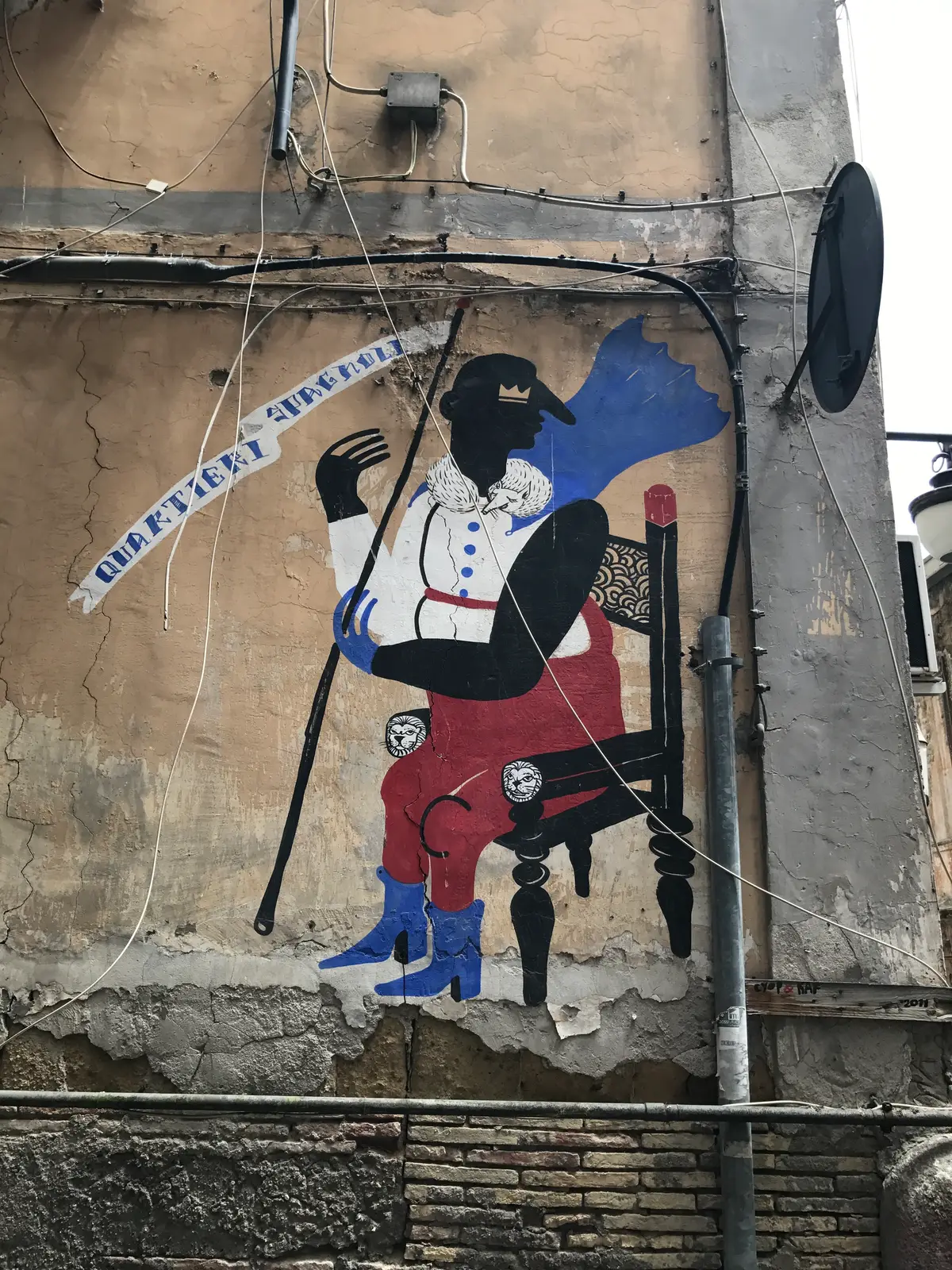 A painted figure with a plumed hat on a wall in the Spanish Quarter, Naples