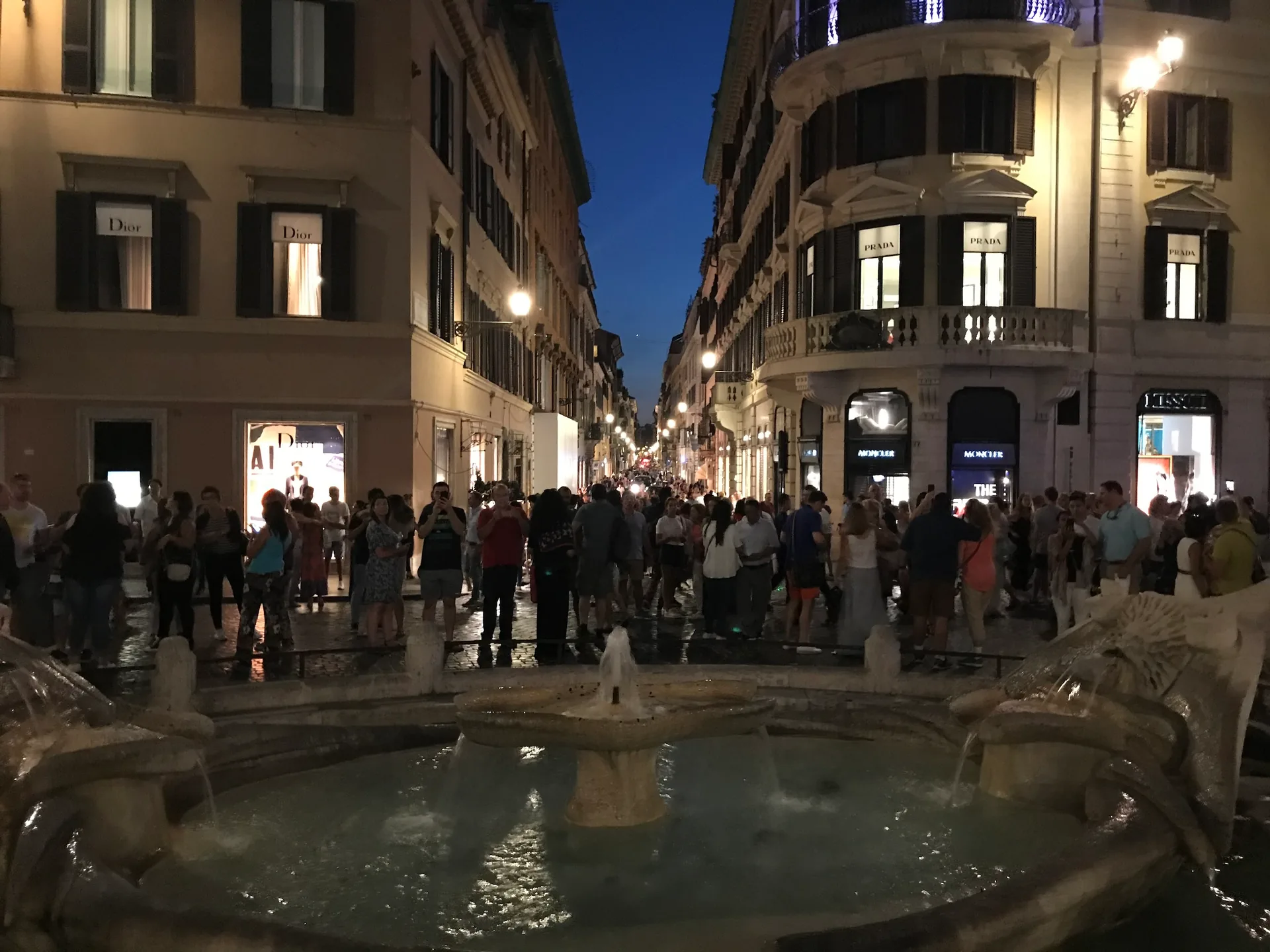 The Barcaccia boat fountain lit at night at the base of the Spanish Steps.