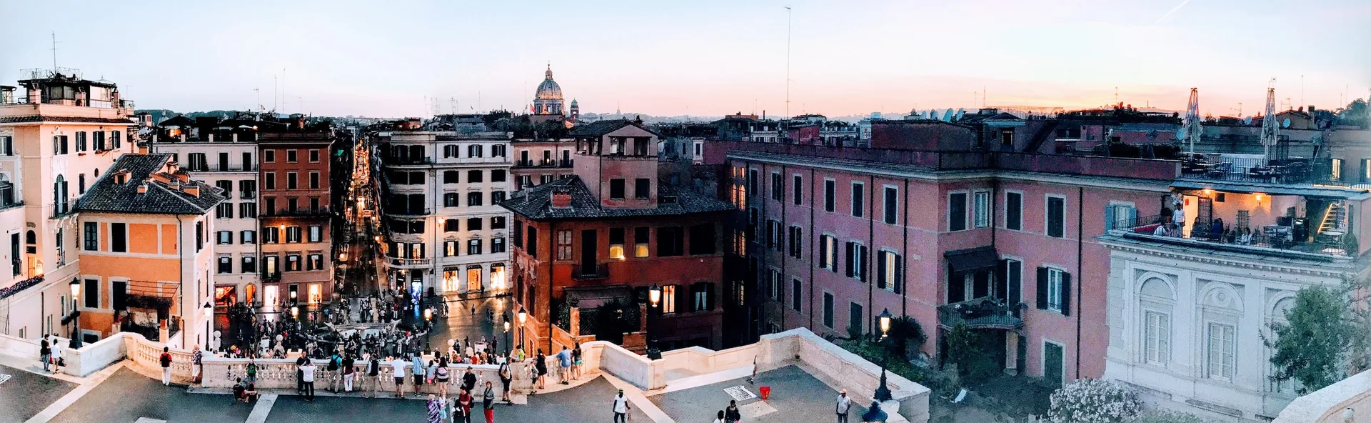 Wide panorama from the top of the Spanish Steps over the piazza at dusk.