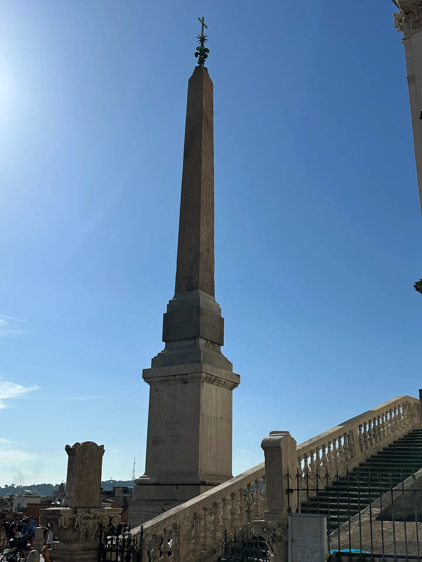 The Sallustian obelisk in front of Trinità dei Monti against a blue sky.